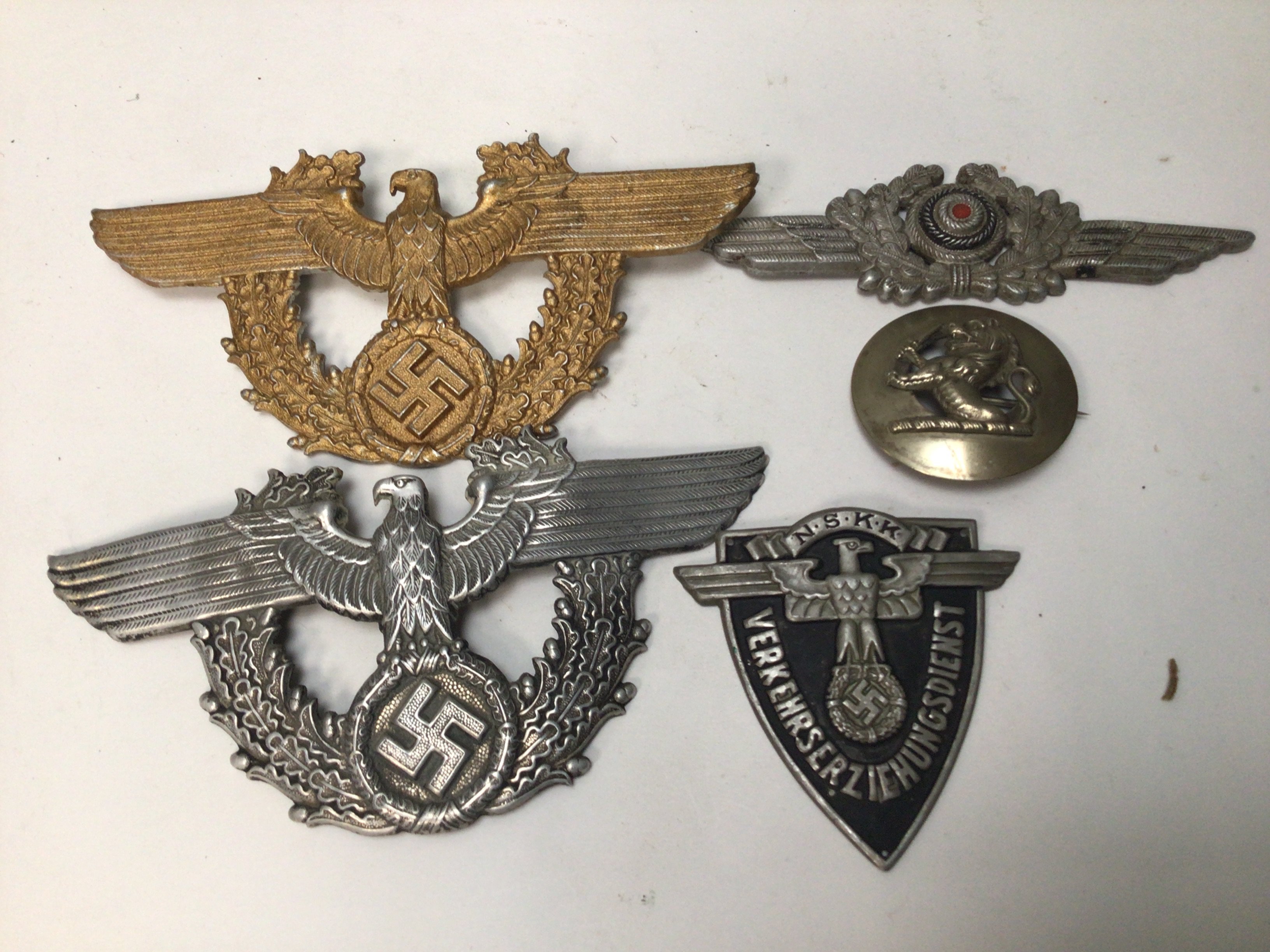 Two German Third Reich Police Shako Plates.Worn on the Nazi police helmet , the gold coloured example still w with both of its screwed fixing pins on the reverse side one other silver finish and Luftwaffe cap plate and two other badges.