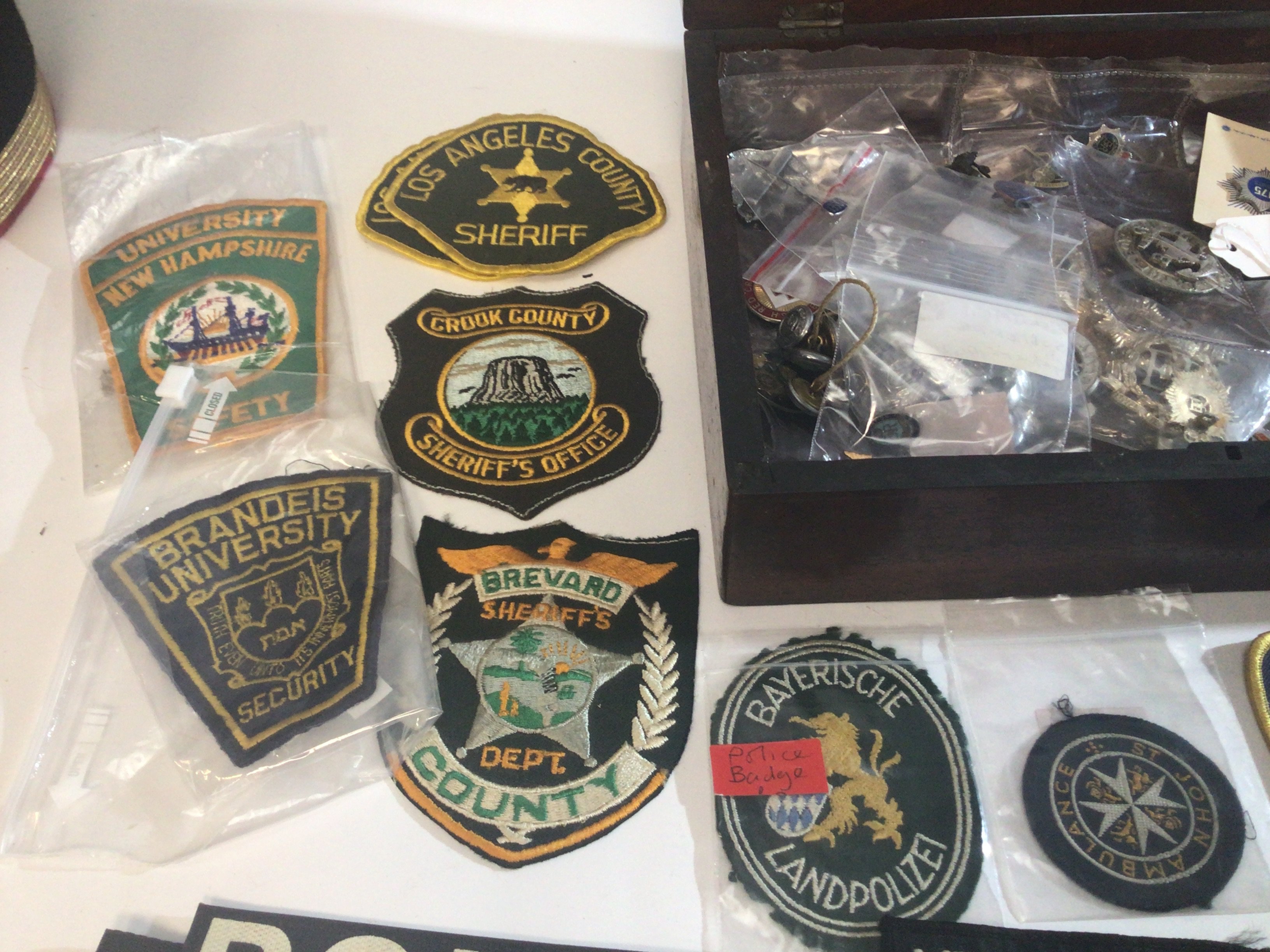 A Mahogany box containing American Police County cloth badges American University Security badges other military police and other associated badges.