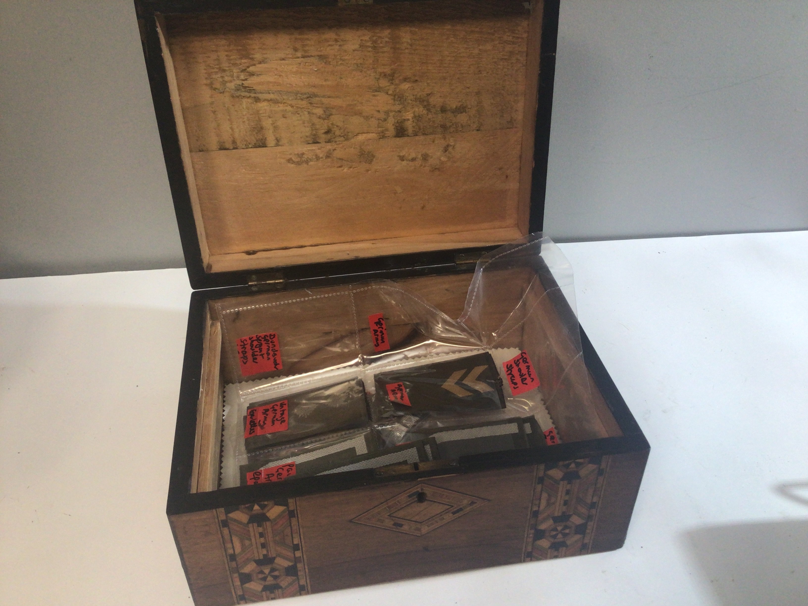 A Walnut inlaid box containing German Army shoulder straps and epaulets.