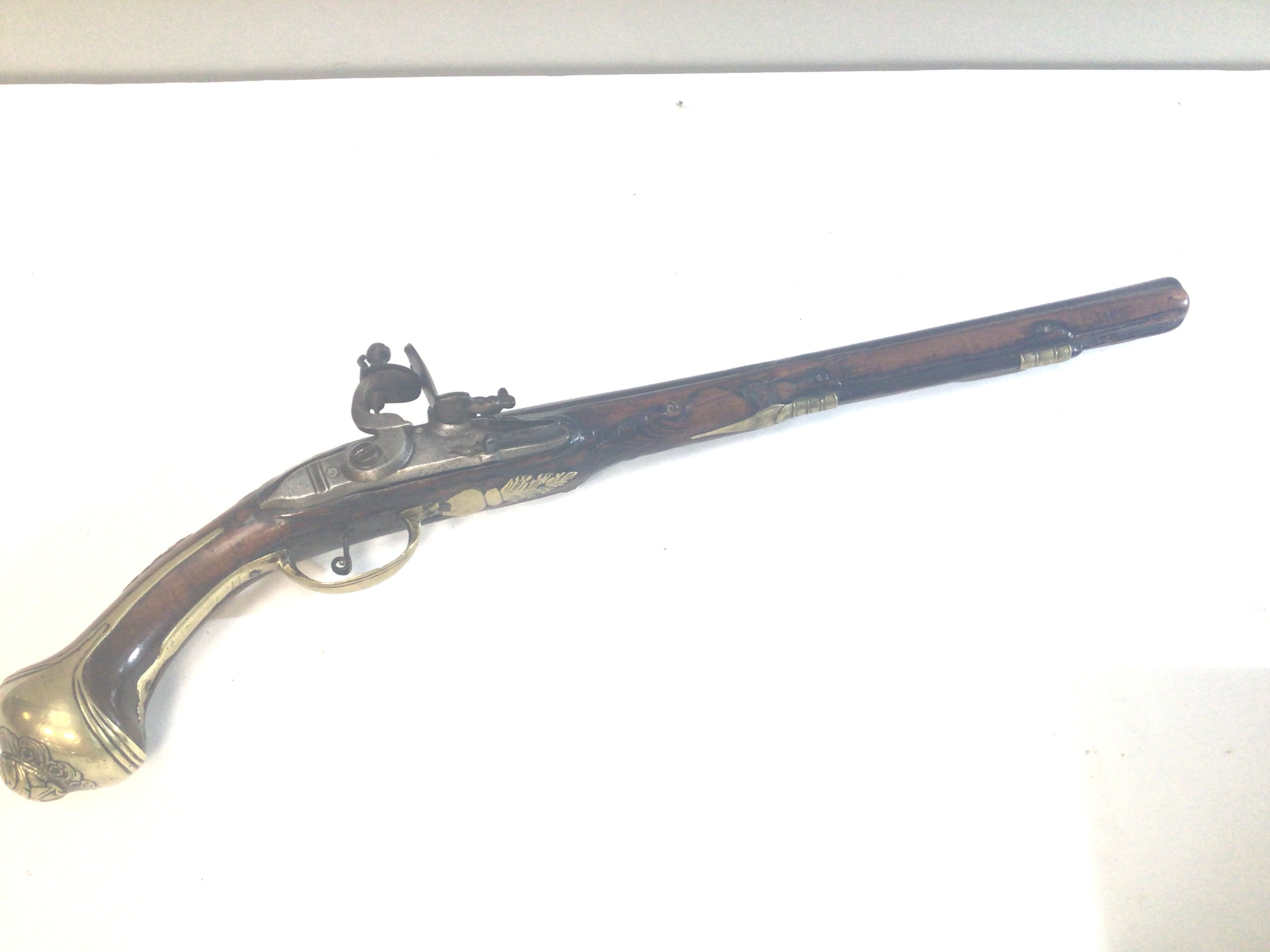 An 18th Century Italian flint lock pistol with a full length carved walnut stock with brass fittings and steel action