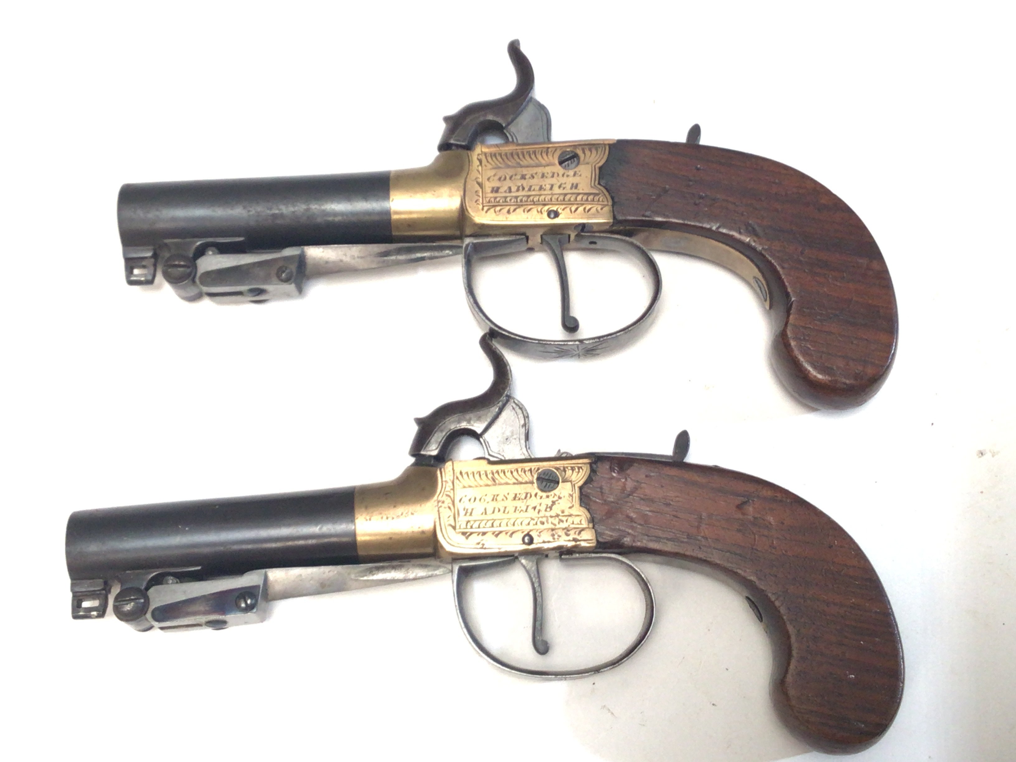 Two matching Percussion 19th century pistols with flick bayonet sliding trigger guard brass slab sided action engraved with makers name Cocksedge Hadleigh twist of steel barrel with proof marks. (2)