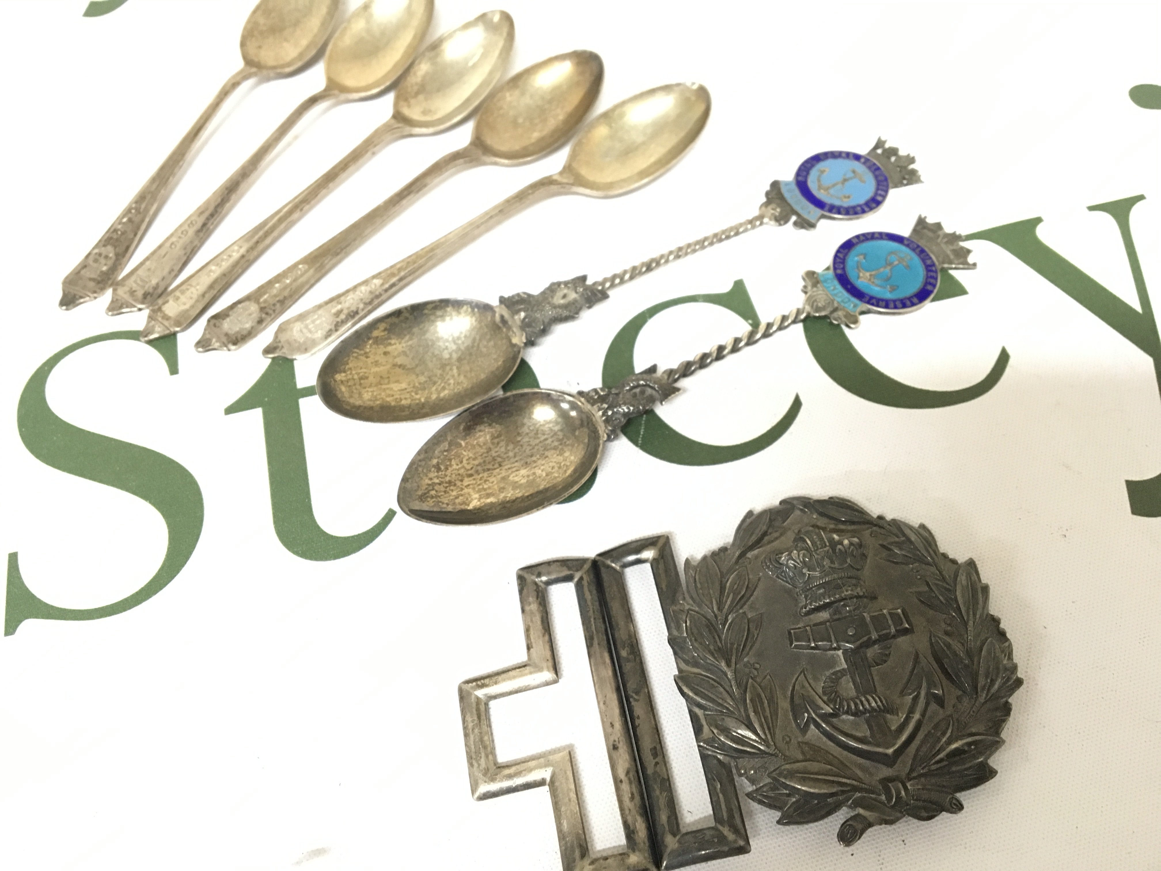 A Silver Royal Navy belt buckle stamped 90 WH with a further mark possible British Chinese Colonial or Honk Kong. Silver and enamel Royal Navy spoons and other silver spoons.