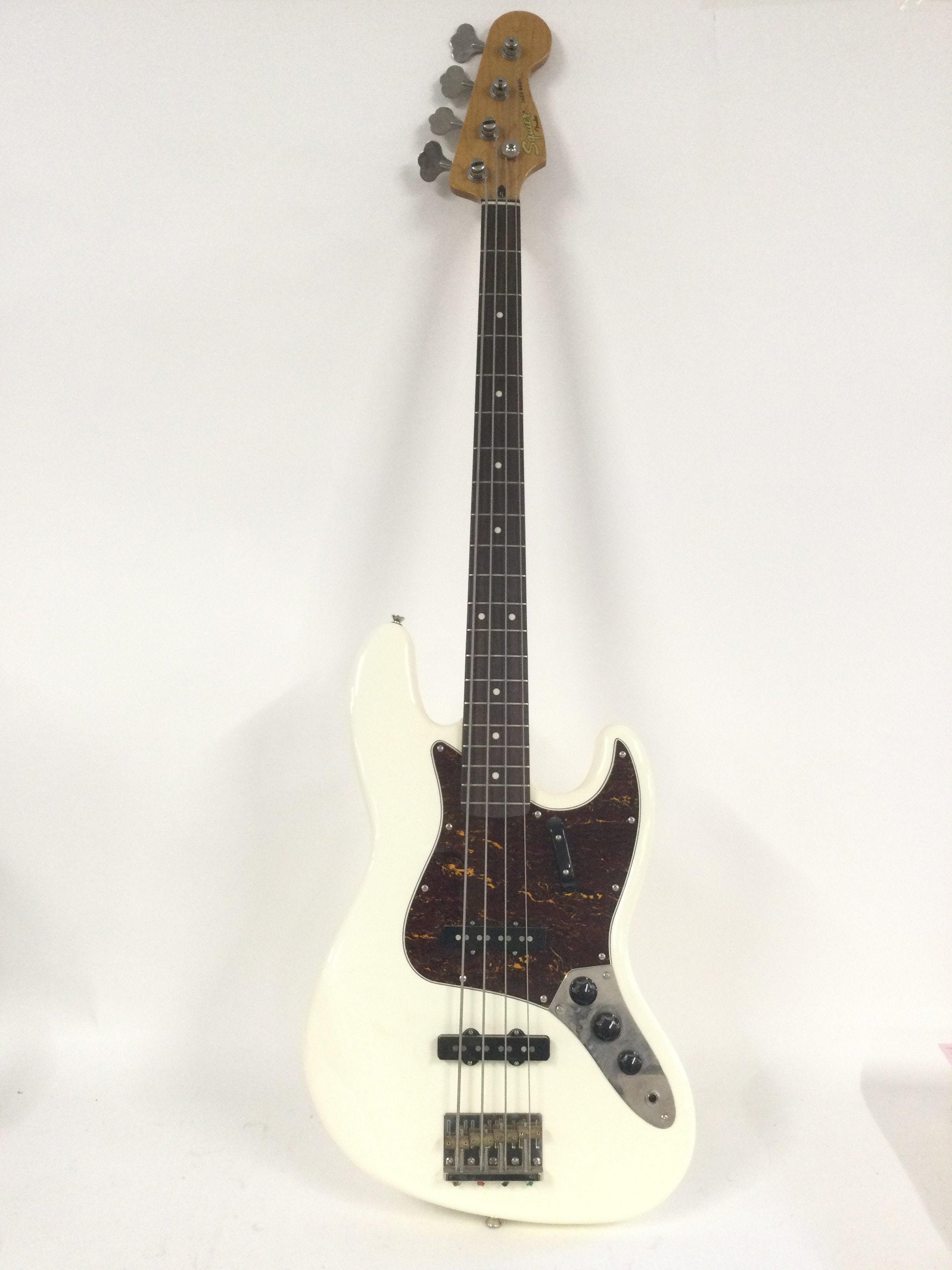 A Fender Squier Jazz bass guitar in white with a tortoishell pickguard. Comes supplied with a hard carry case.