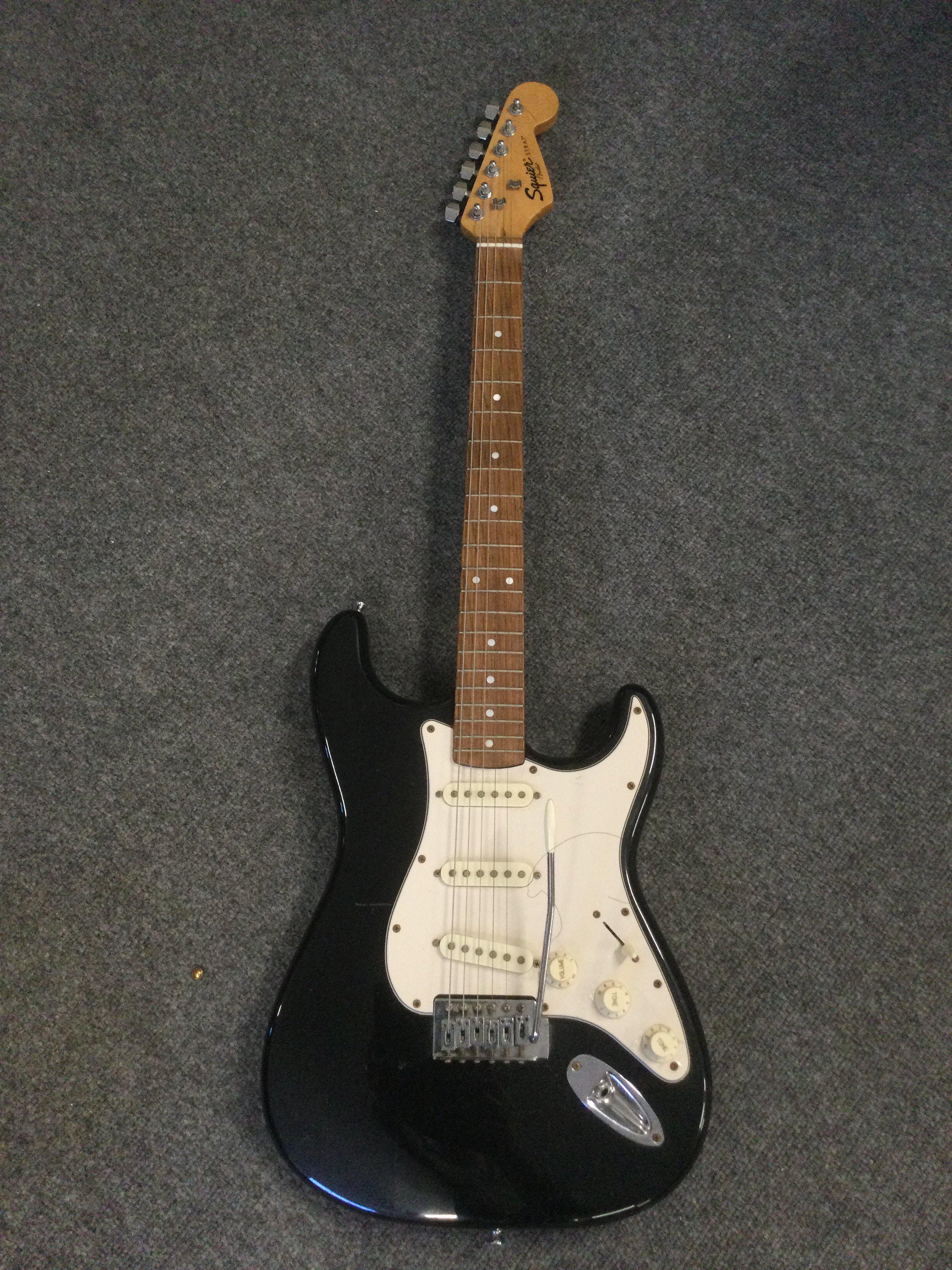 A Fender Squier Stratocaster electric guitar and a small practice amp (2).