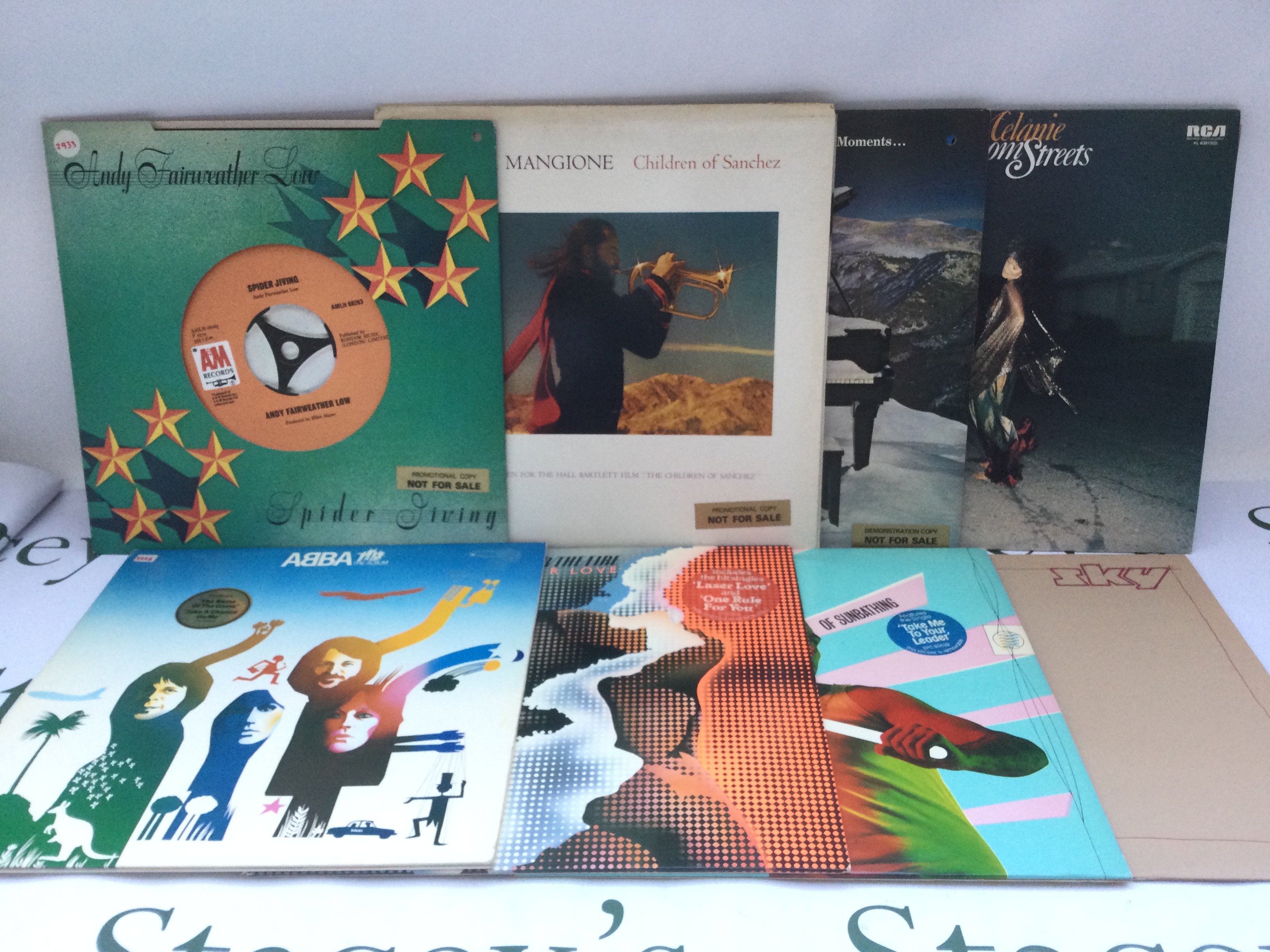 Two bags containing 23 promo copy LPs and 12" singles by various artists including Marc Bolan, Meat Loaf, Jeff Beck Group, Abba and others.