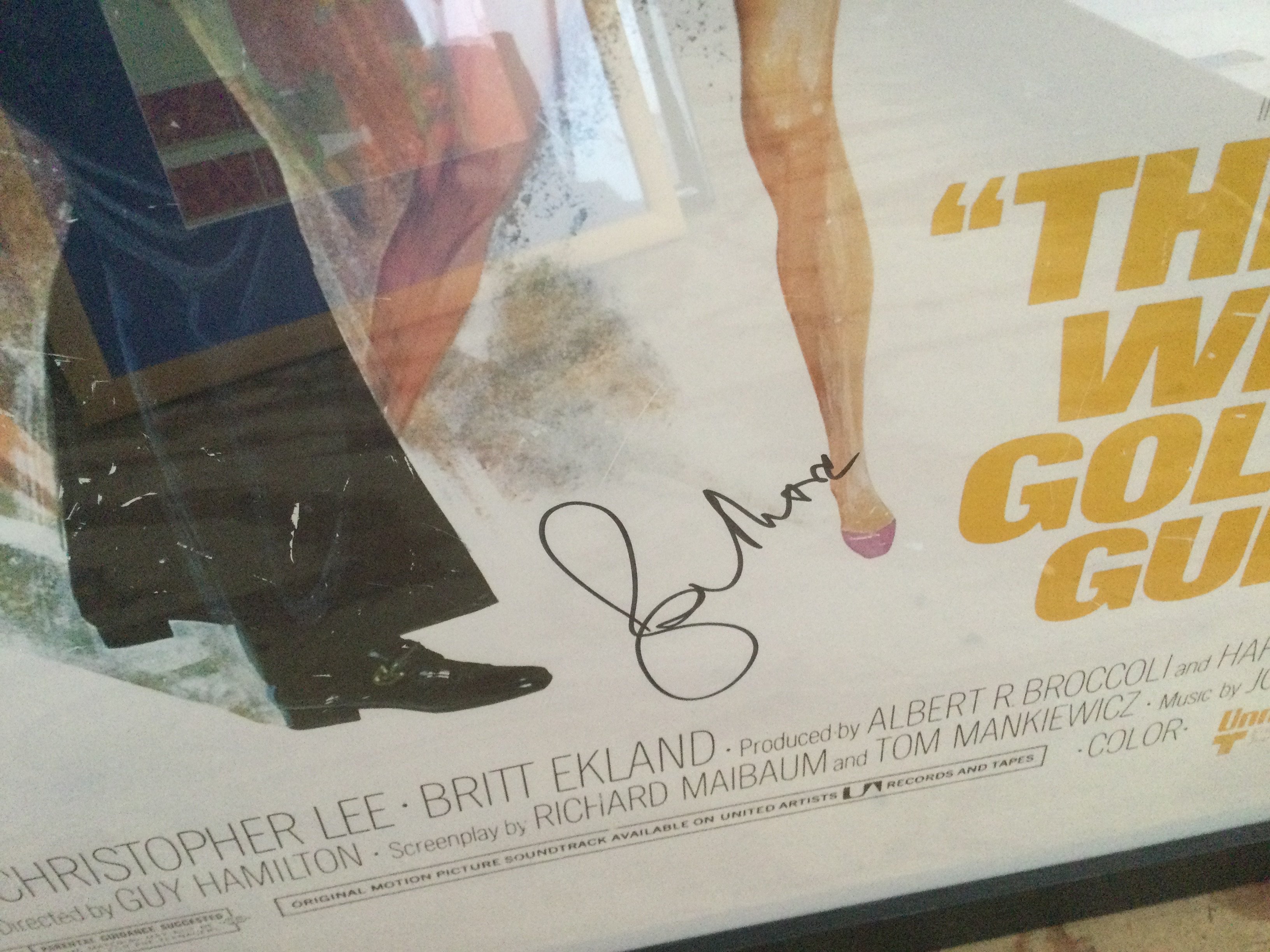 A framed and glazed James Bond film poster for 'The Man With The Golden Gun' signed by Sir Roger Moore with COA. Approx 66cm x 96cm including frame.