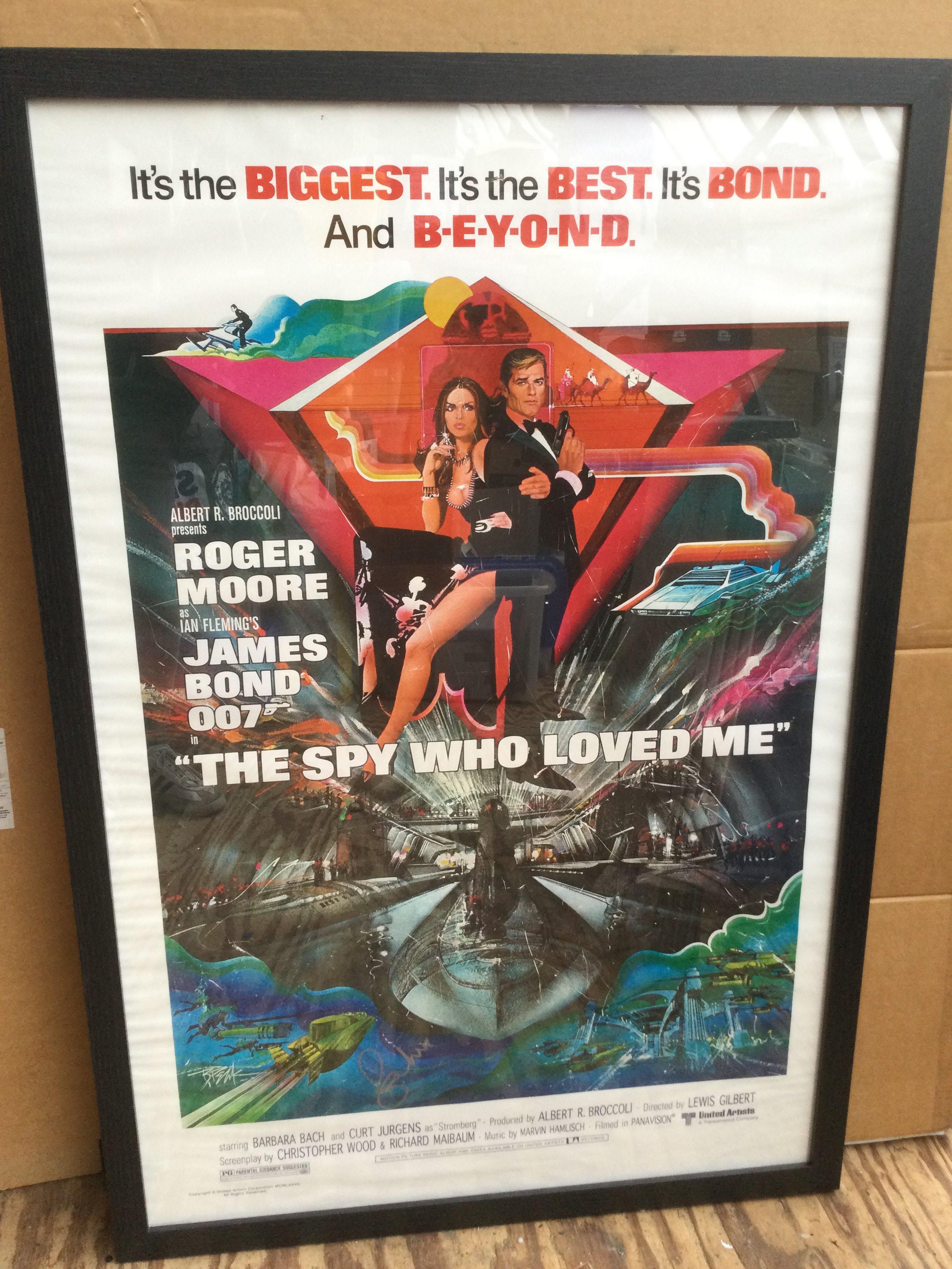 A framed and glazed James Bond film poster for 'The Spy Who Loved Me' signed by Sir Roger Moore with COA. Approx 66cm x 96cm including frame.