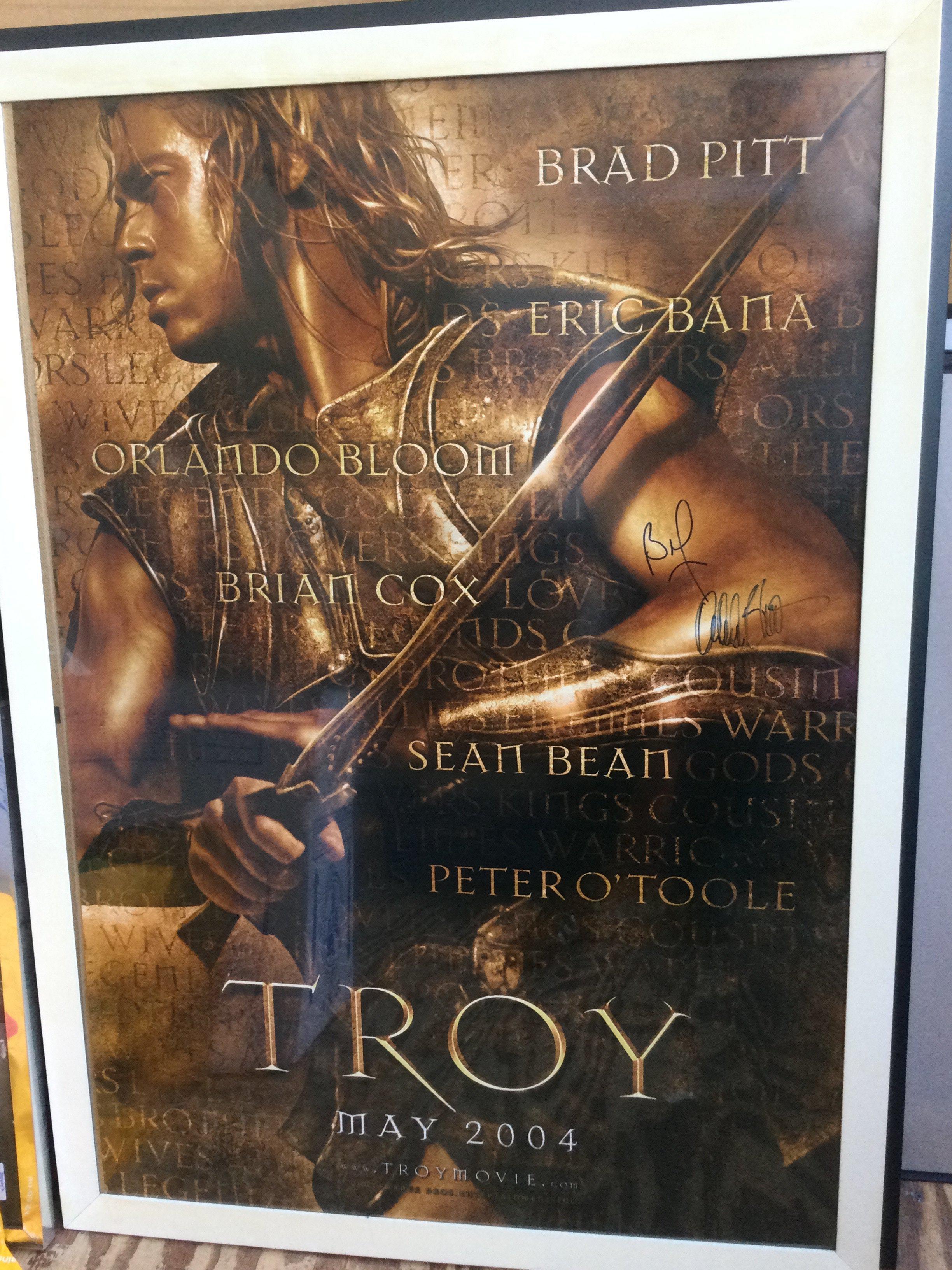A signed US one sheet film poster for the 2004 movie Troy, signed by Brad Pitt and Orlando Bloom. Framed and glazed, not folded.
