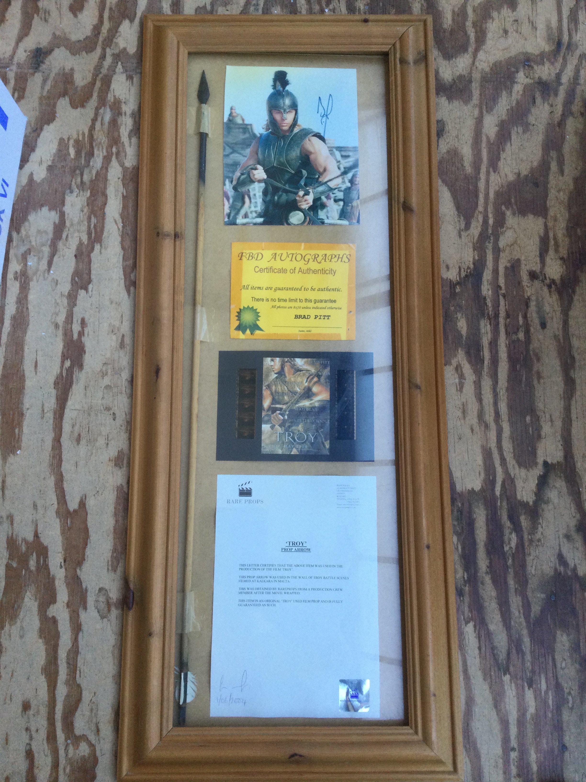 A Troy movie display containing a screen used prop arrow and signed Brad Pitt photo.