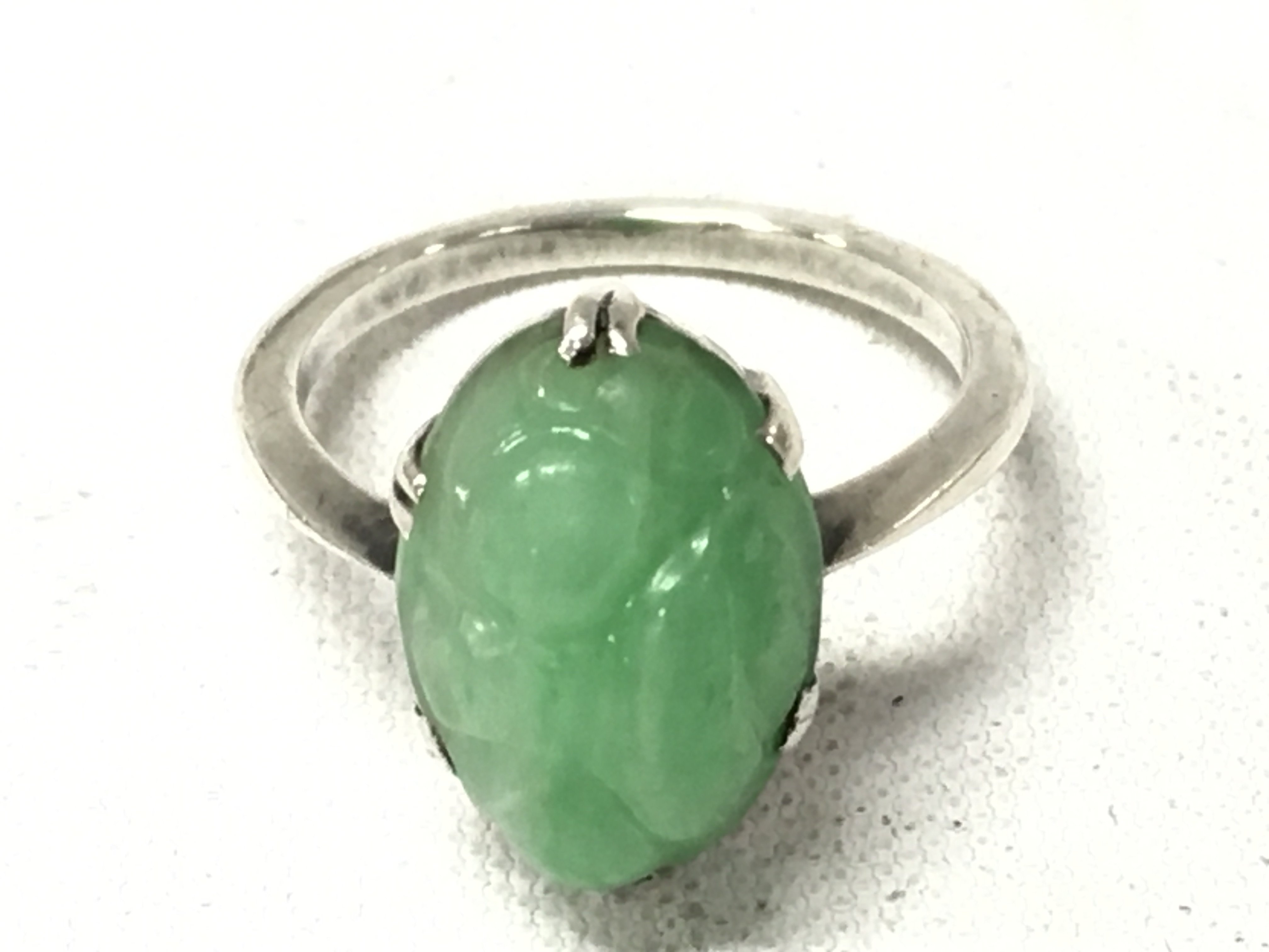An unmarked white metal ring set with jade, ring size K. Postage cat A