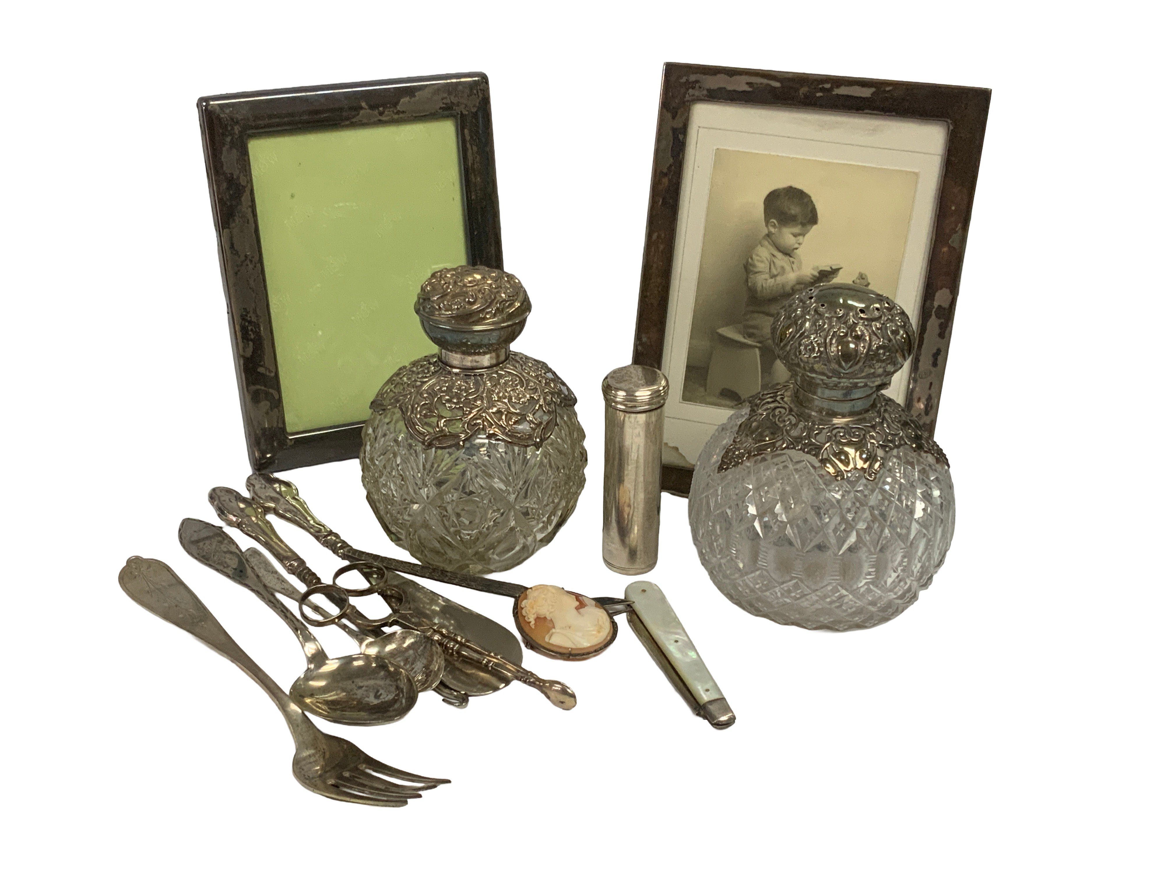 A mixed lot to include. Two hallmarked silver topped scent bottles, 2 Hallmarked silver picture frames, Hallmarkd silver cutlery etc.