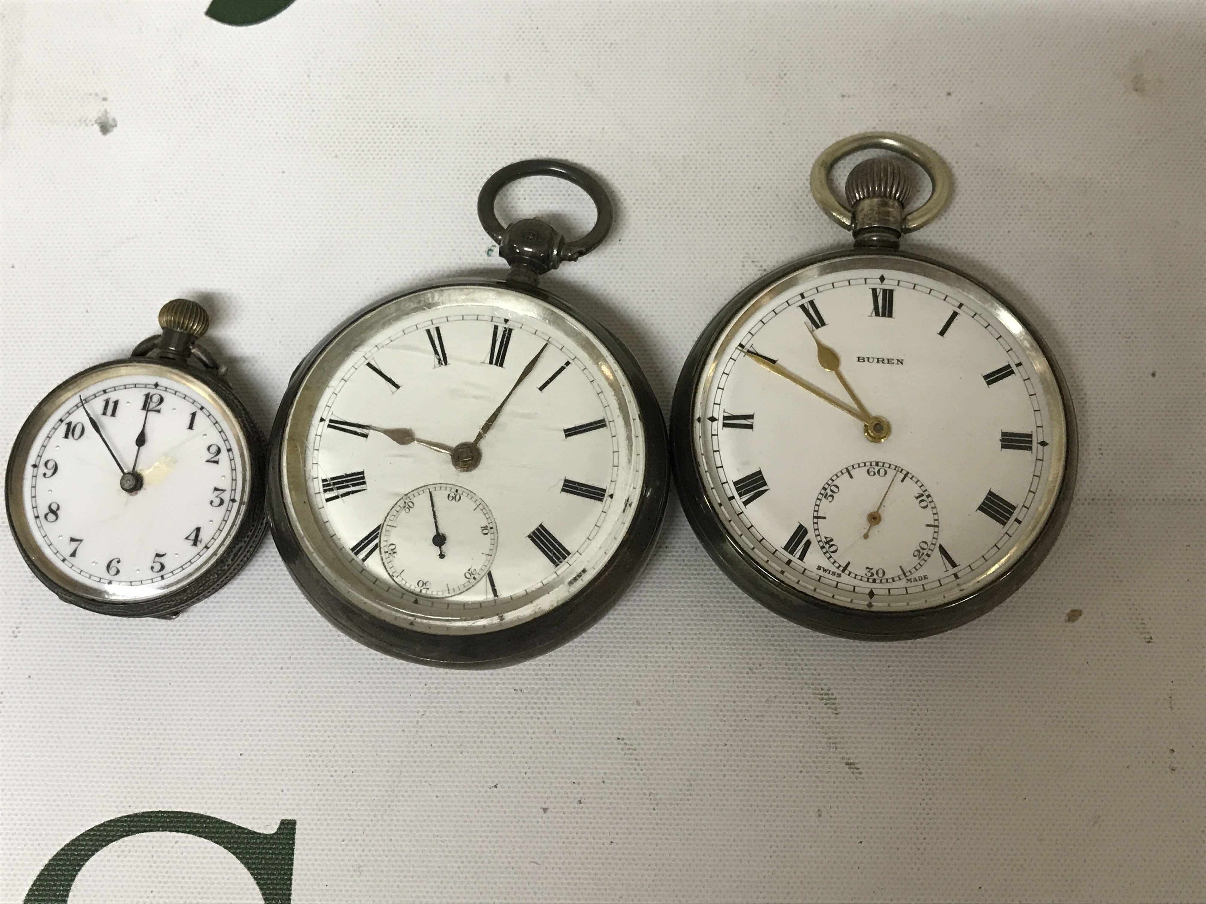 Three silver pocket watches with Roman and Arabic numerals.