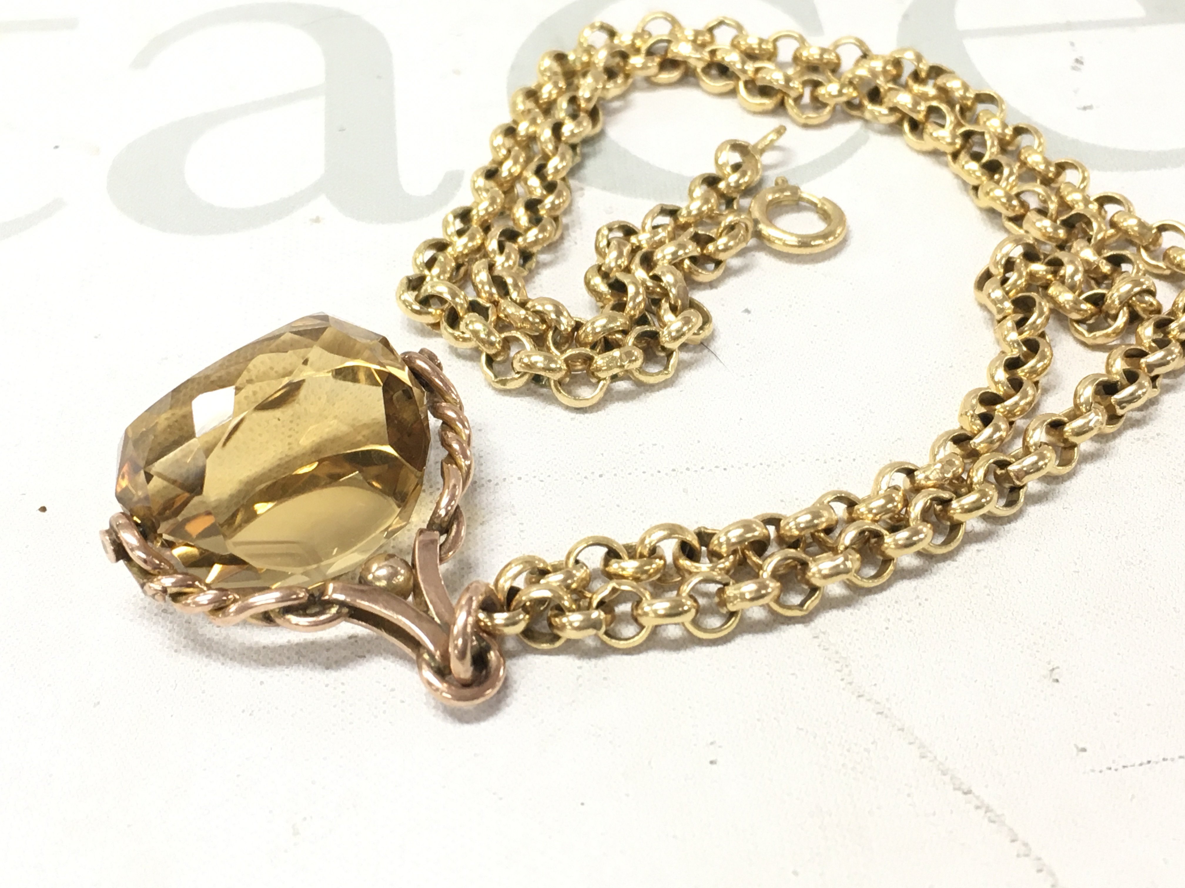 A 9ct rose gold spinning fob attached to a yellow metal belcher chain.