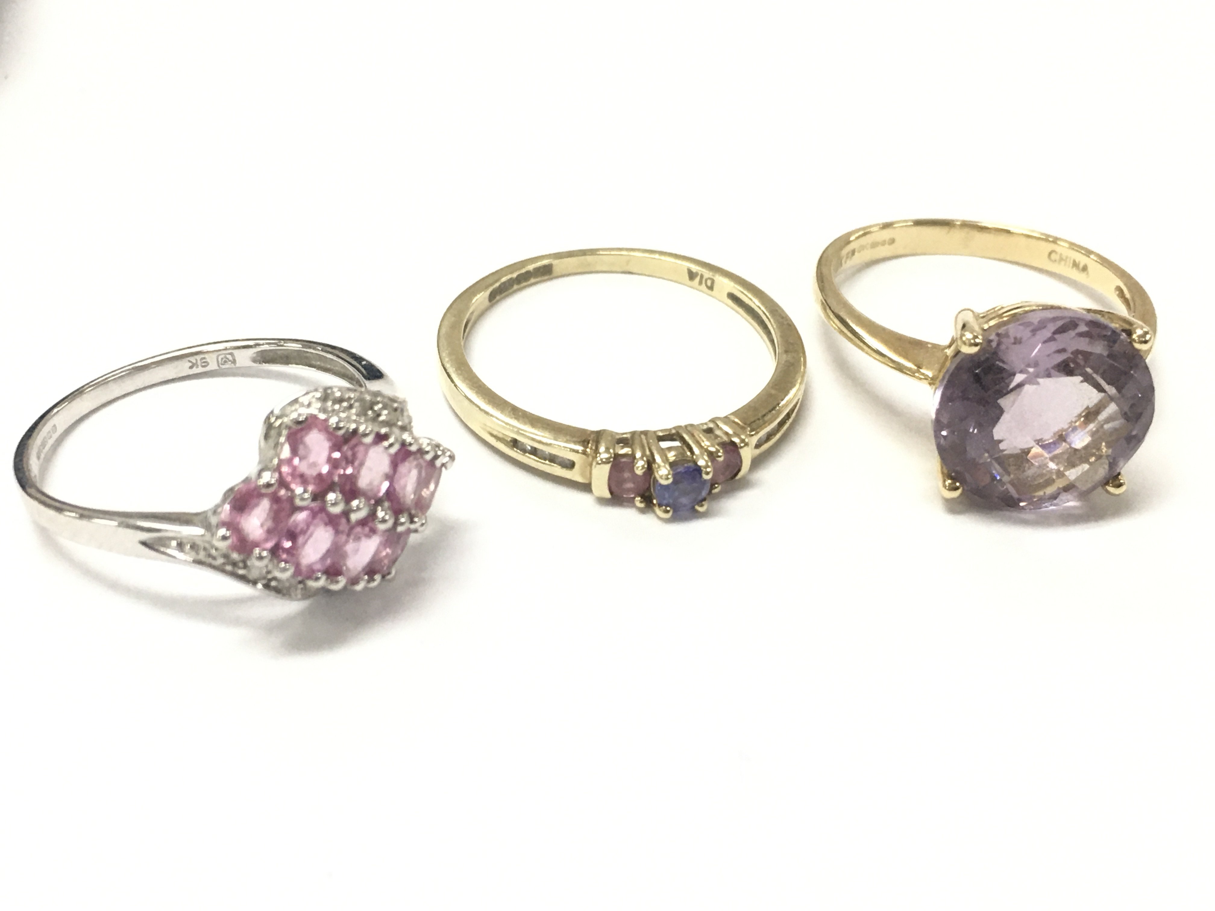 9ct gold rings including a white gold pink sapphire and diamond chip ring size N, pink amethyst cocktail ring size P, Tanzanite pink sapphire and diamond chip ring size R/Q. 7.6g total weight. postage catA