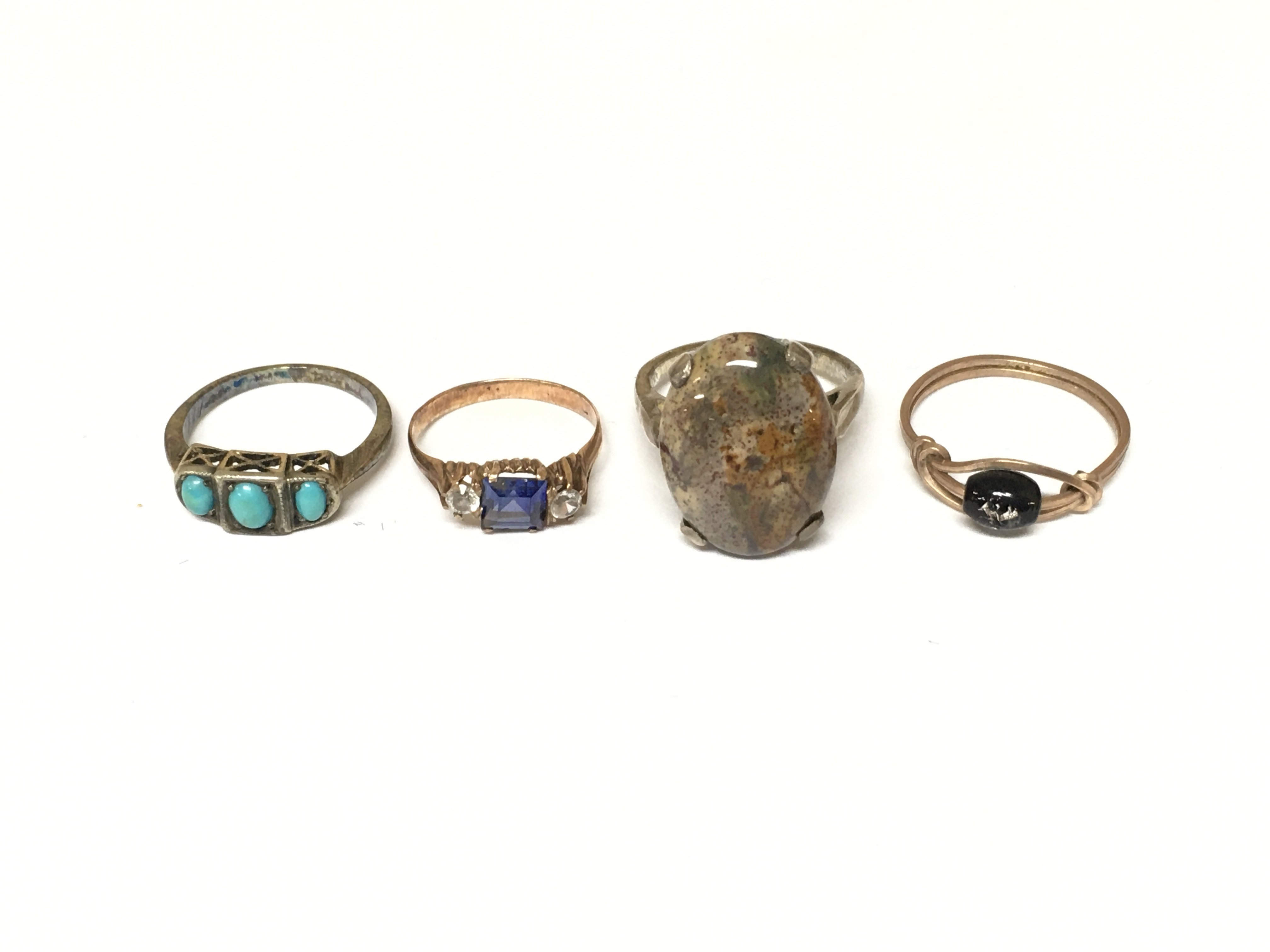 A collection of four assorted rings set with assorted gems and stone.
