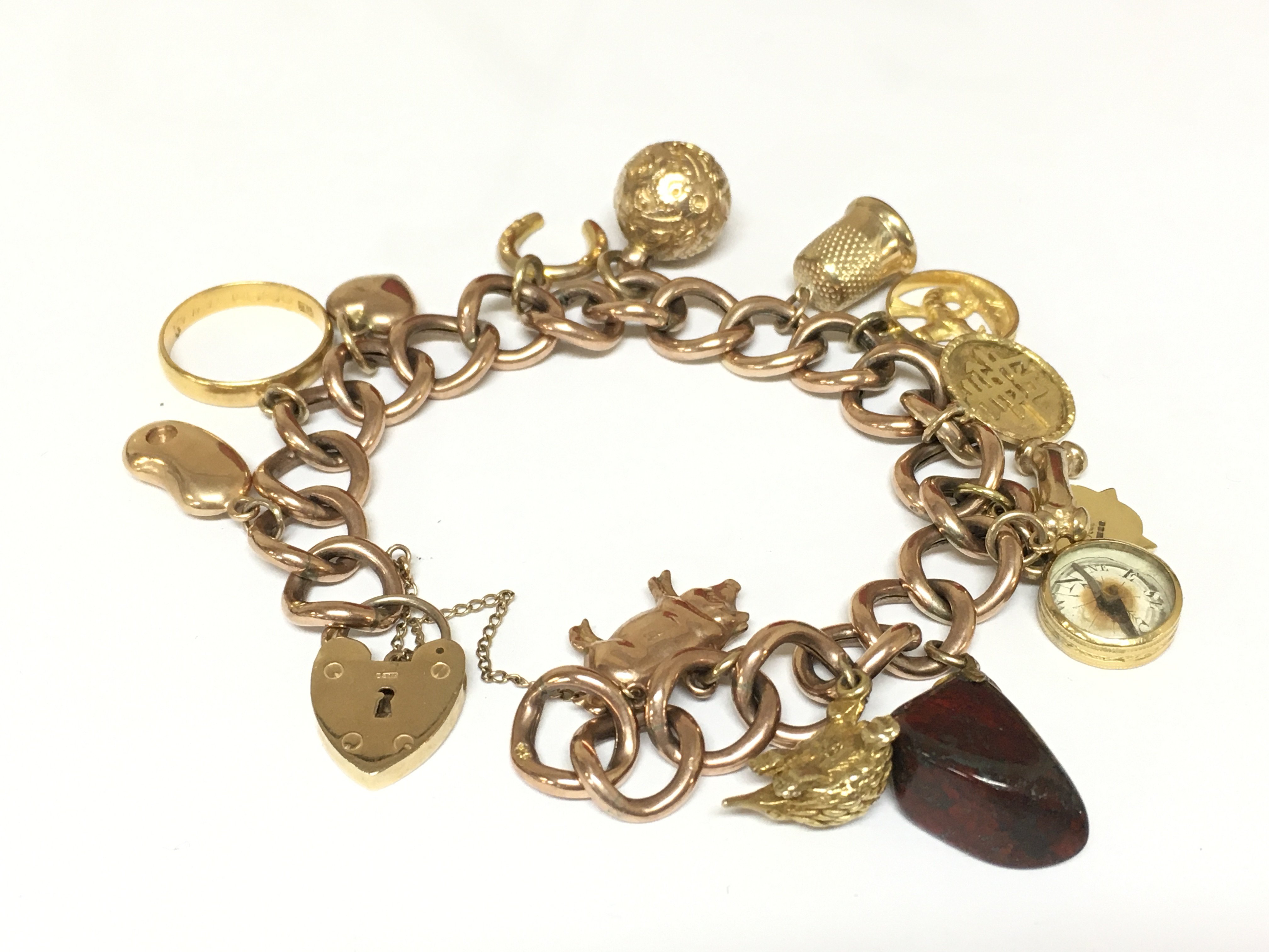 A 9ct gold charm bracelet with multiple charms including a 22ct gold band. Approximately 42g