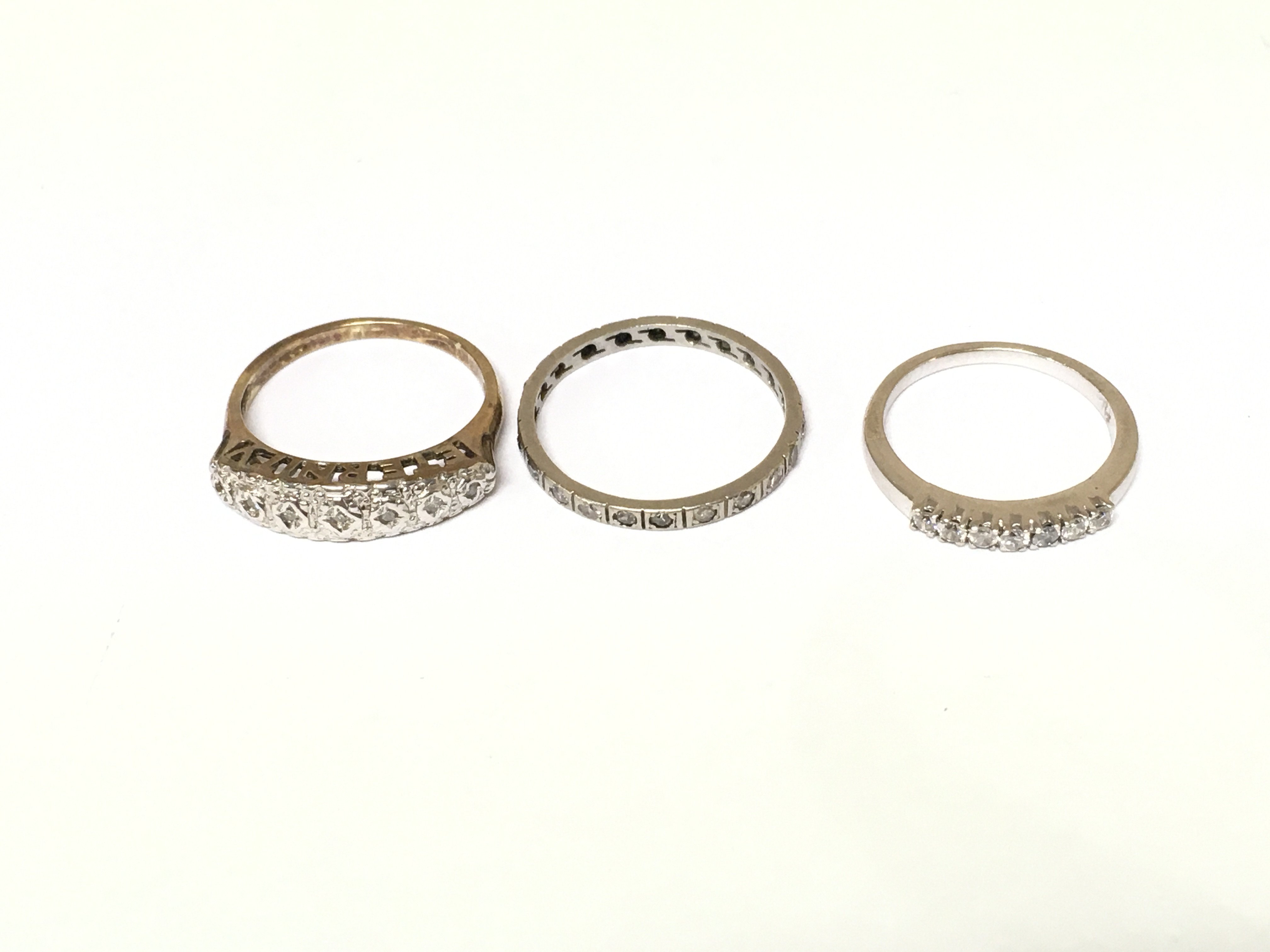 A 9ct gold diamond half eternity ring 2.22g and two white metal rings one with diamonds and one with white stones. Sizes I M and N