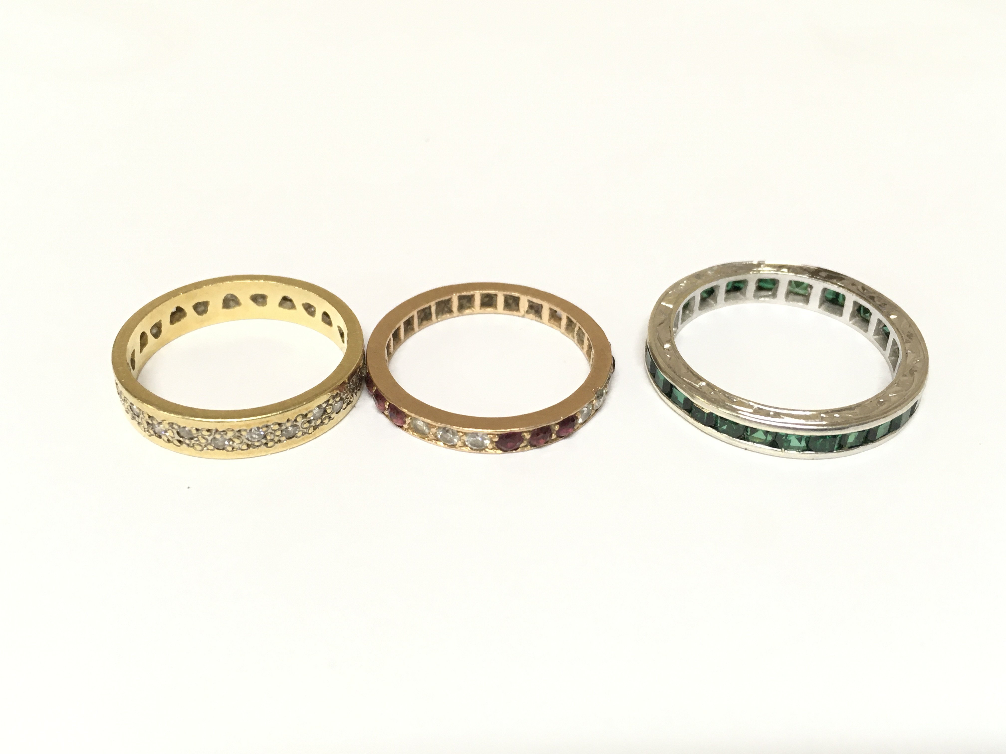 Three unmarked rings set with various gems including diamonds. Approximately 7.3g and sizes K & N