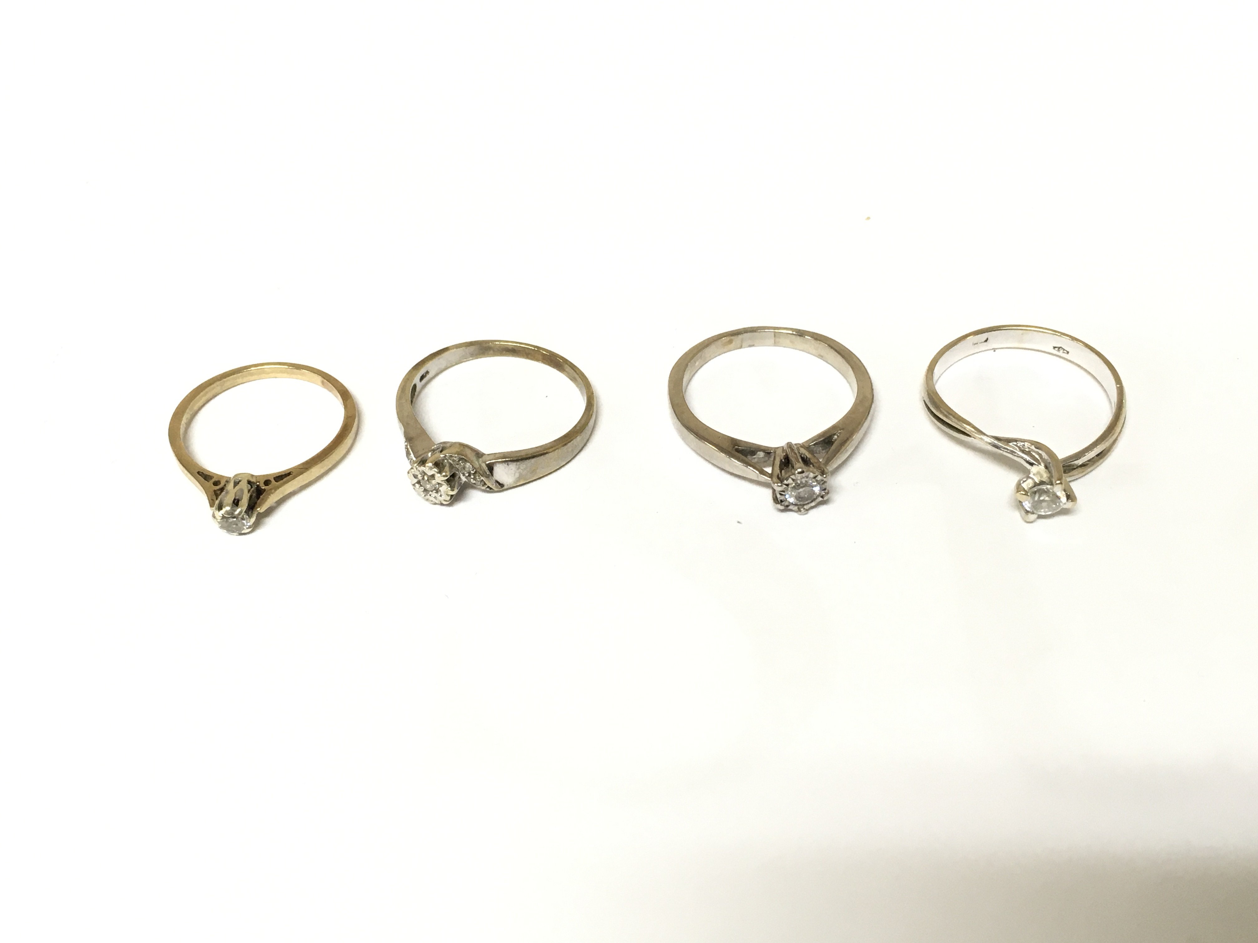 Four unmarked rings three with diamond and one with white stones. Approximately 10.10g Size K O & P