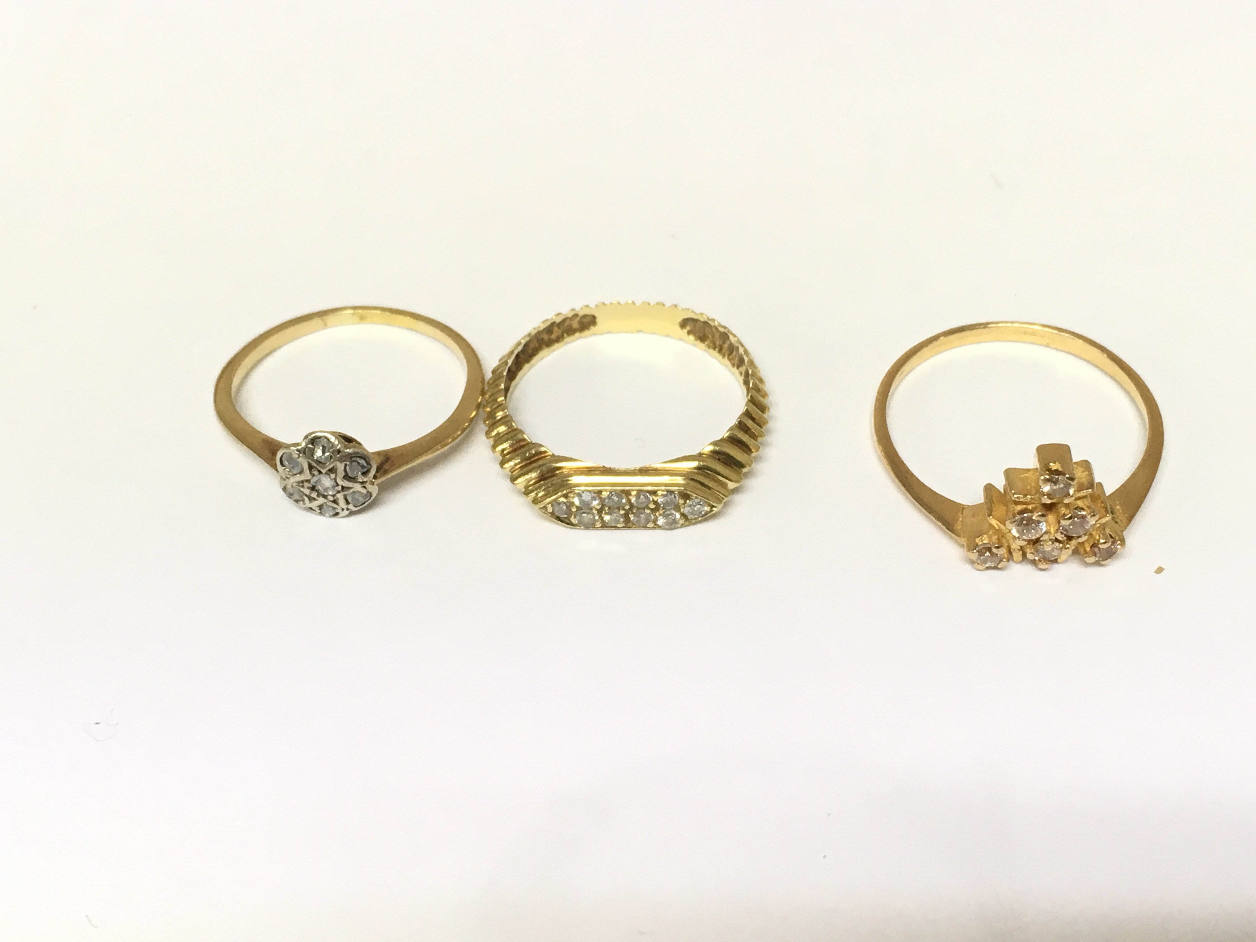 Three unmarked rings two set with diamonds and one set with white stones. Approximately 6.4g and sizes L N & P