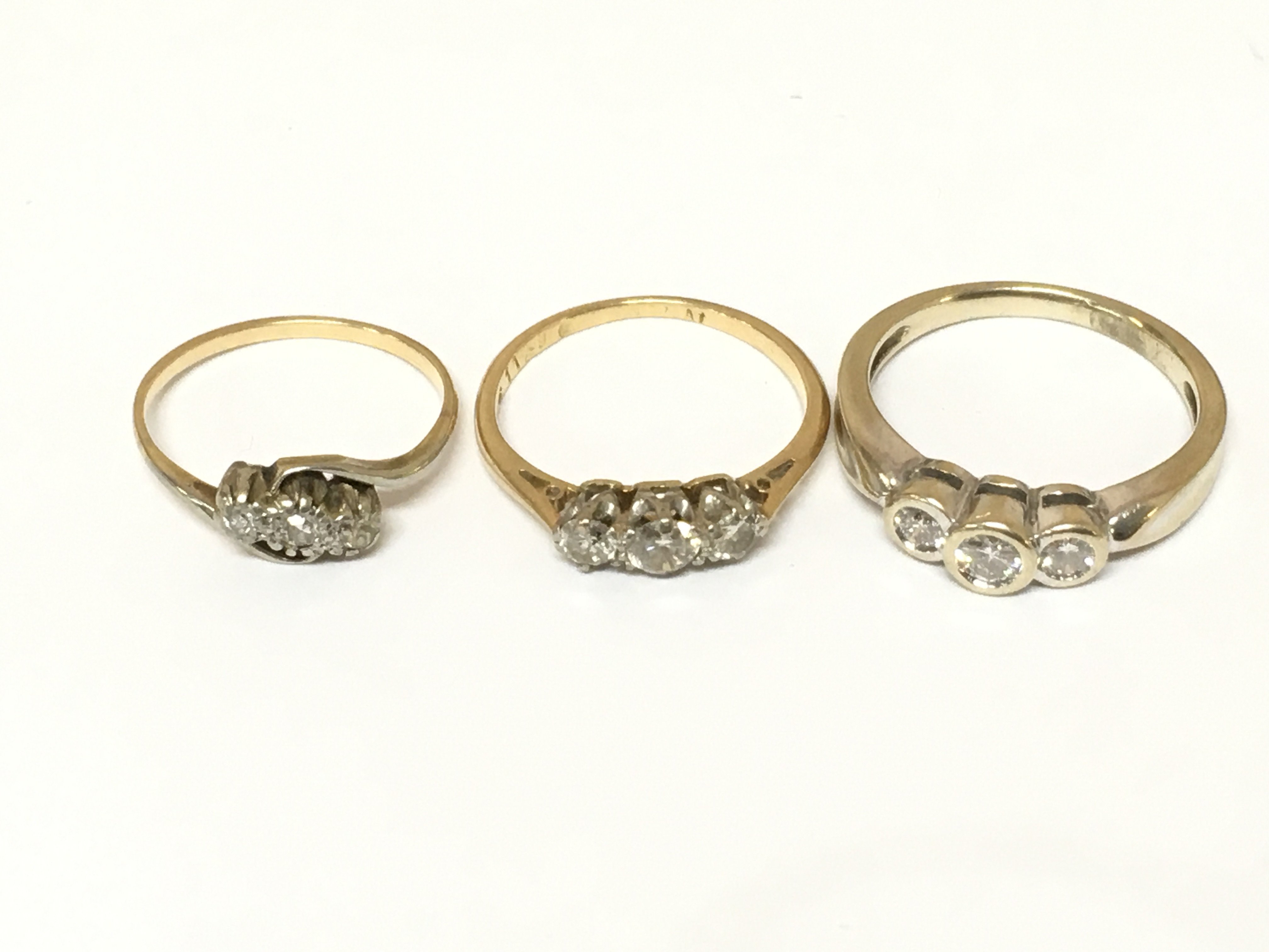 Three unmarked three stone diamond rings. Approximately 7.4g and sizes J L and M1/2