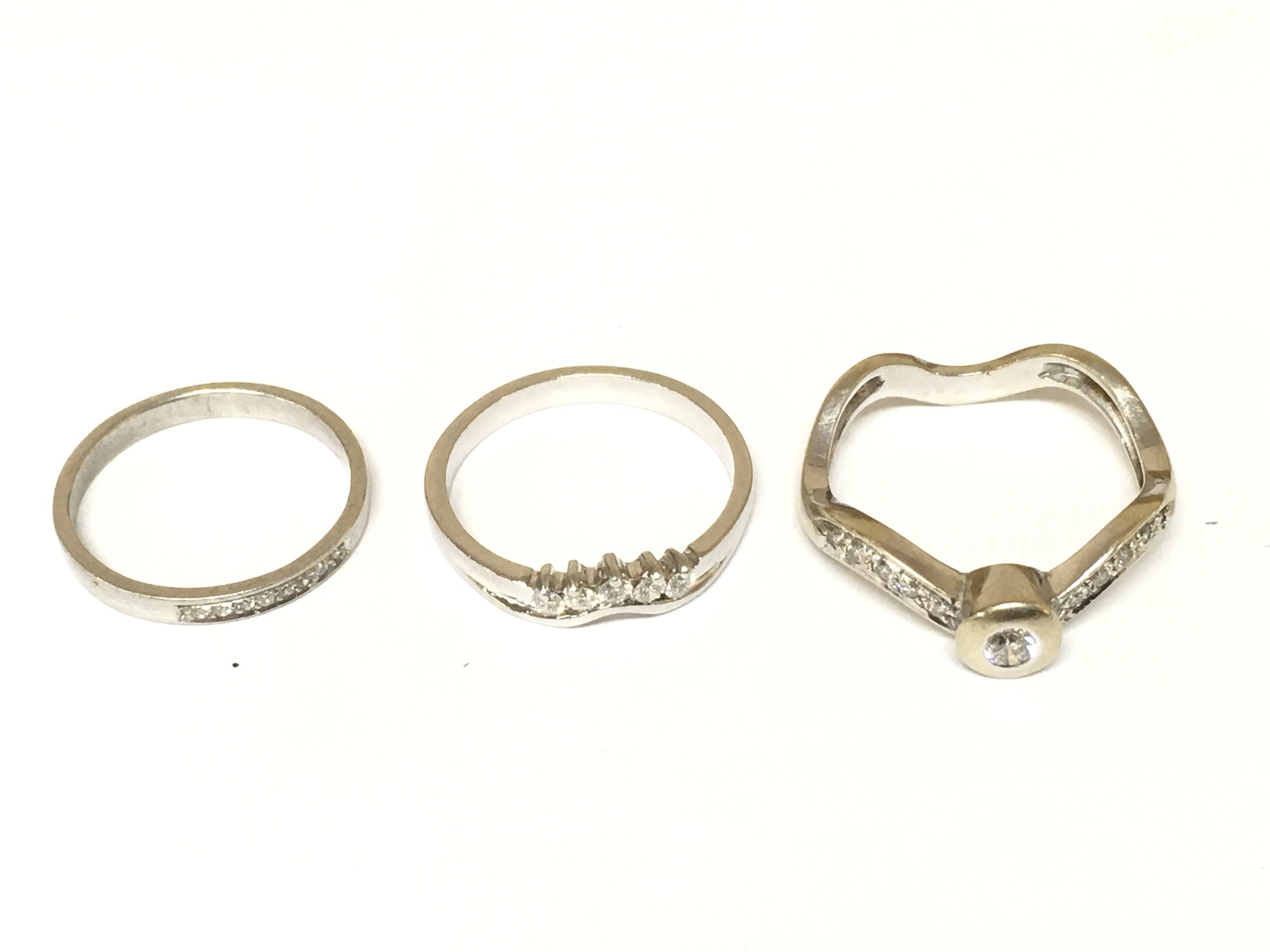 Three white unmarked rings two set with diamonds. Approximately 9g and sizes L 1/2 N 1/2 and R