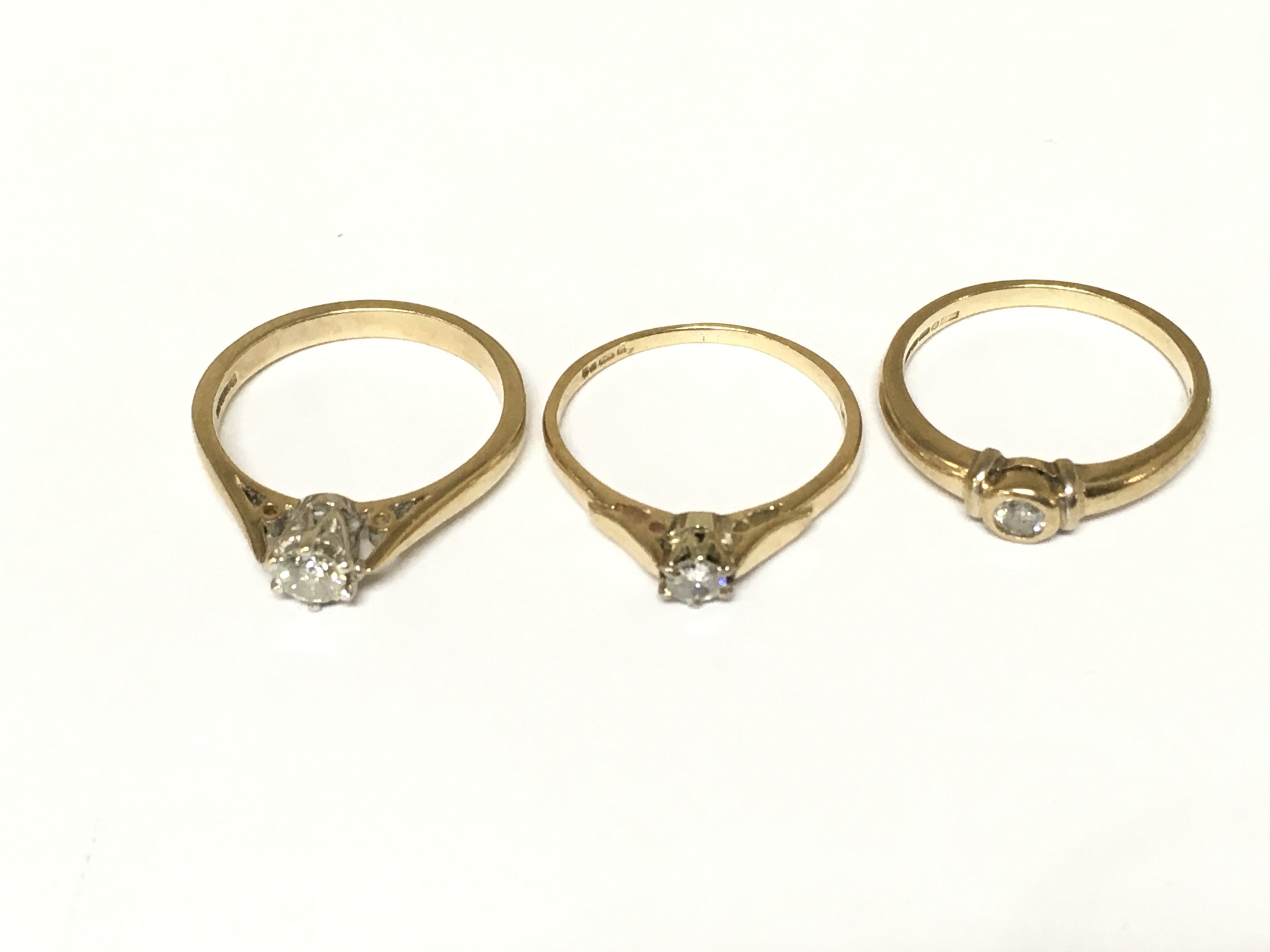 Three 9ct gold diamond solitaire rings. Approximately 6g and sizes M 1/2 and N
