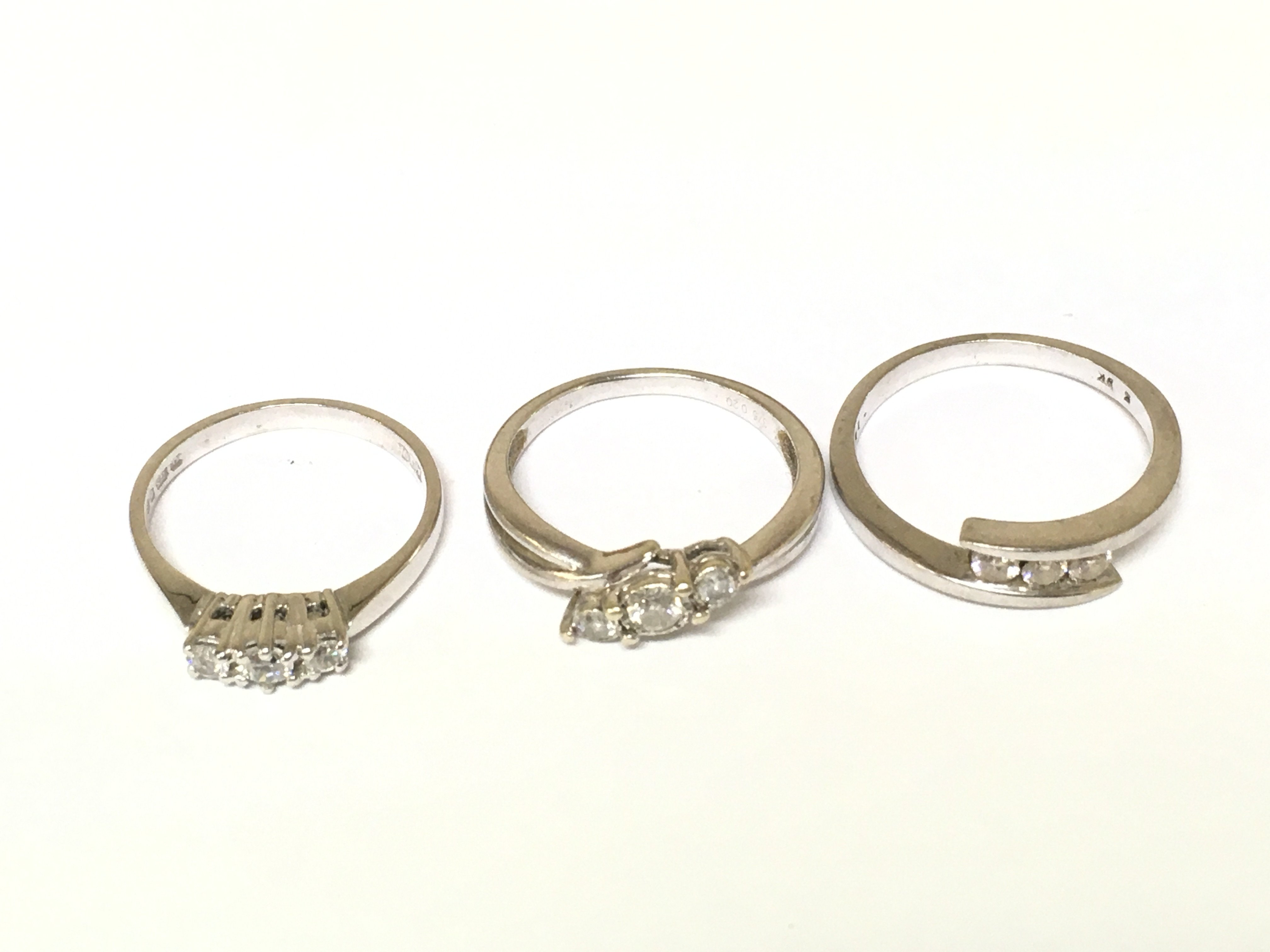 Three 9ct white gold three stone rings two with diamonds one with white stones. Approximately 7.6g and sizes L N 1/2 and P