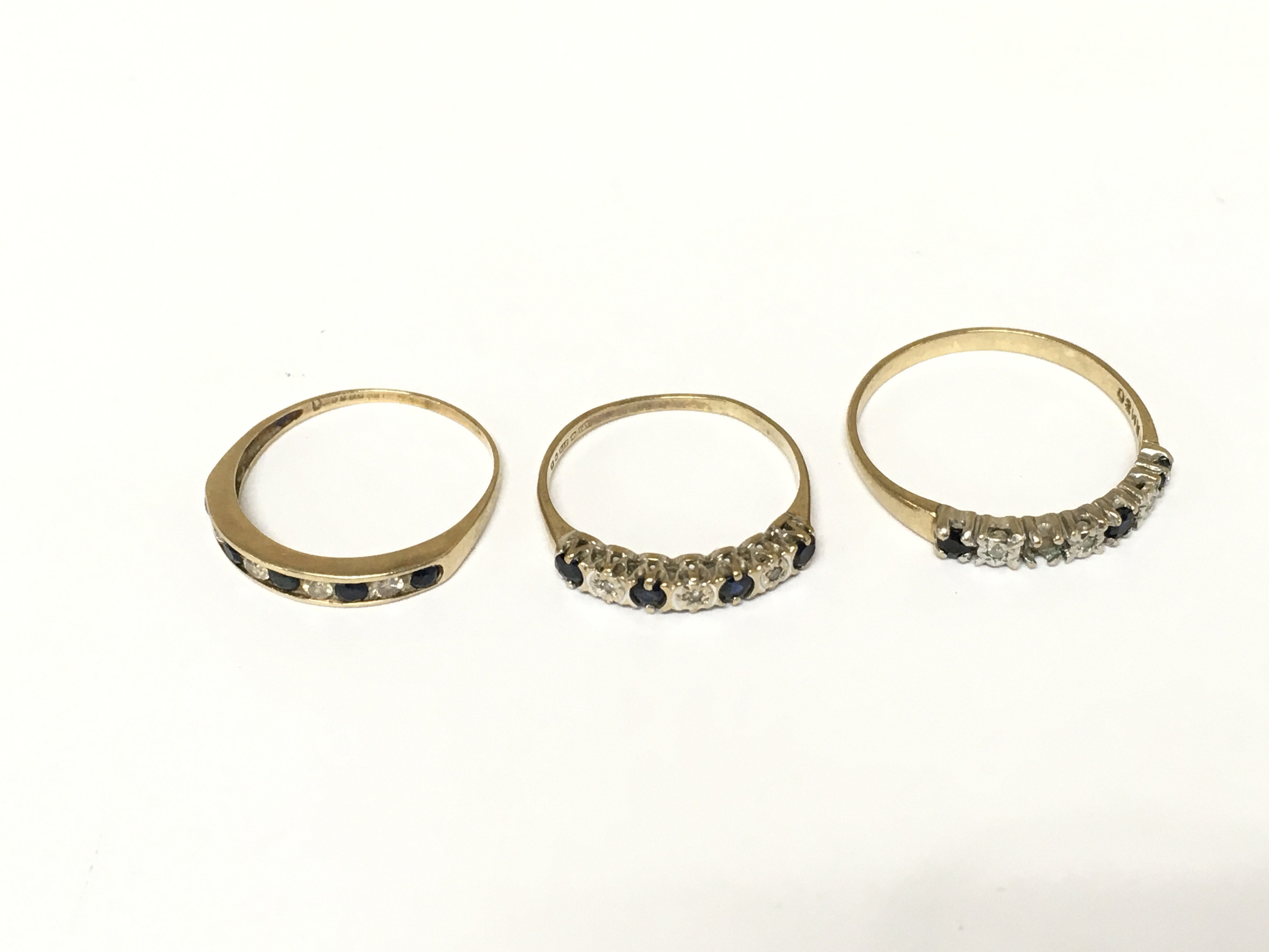 Three 9ct gold diamond and sapphire half hoop rings. Approximately 4.7g and sizes P and V