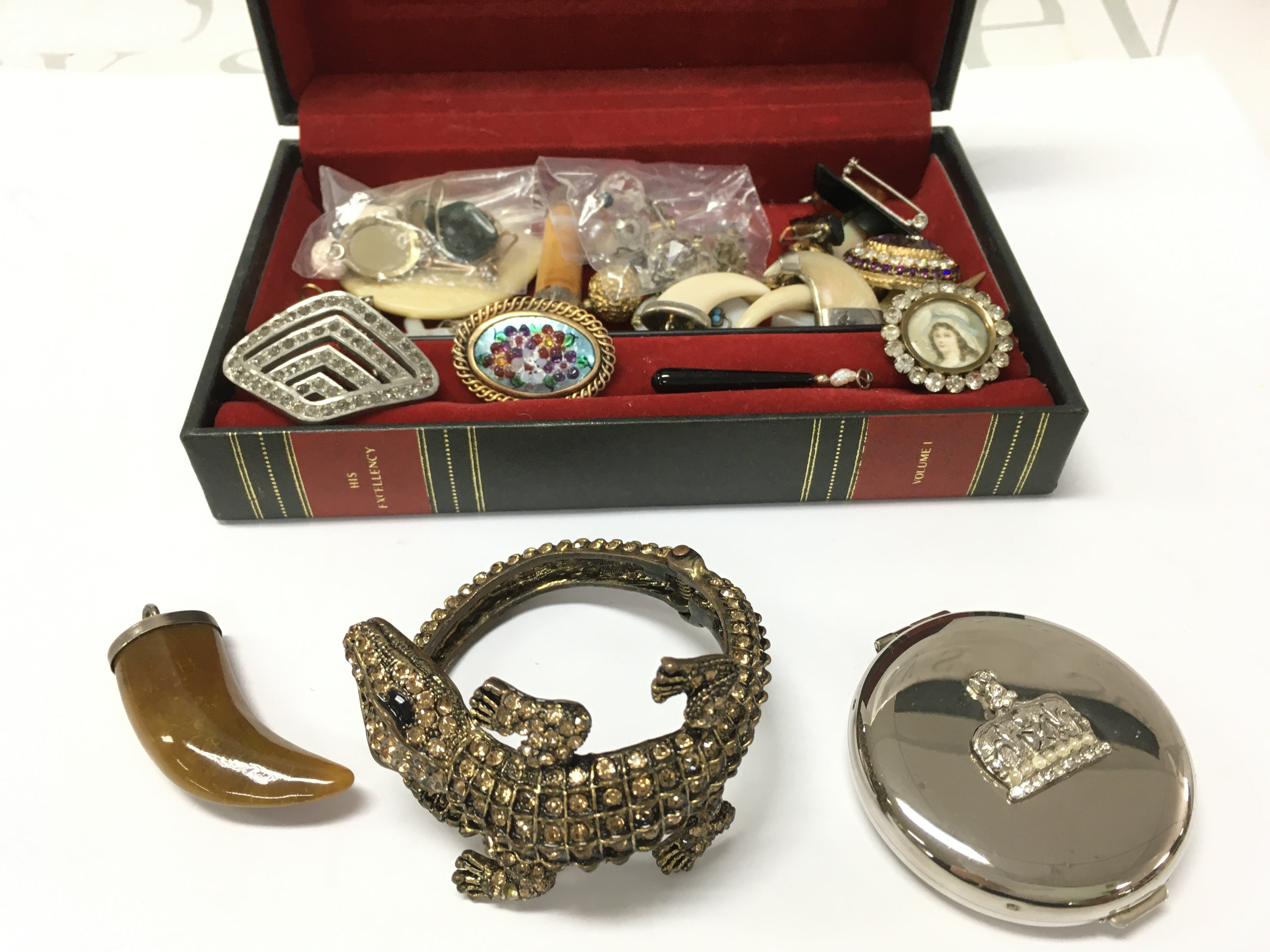 a box of interesting jewellery and other items including pendants , pins etc . Postage category B