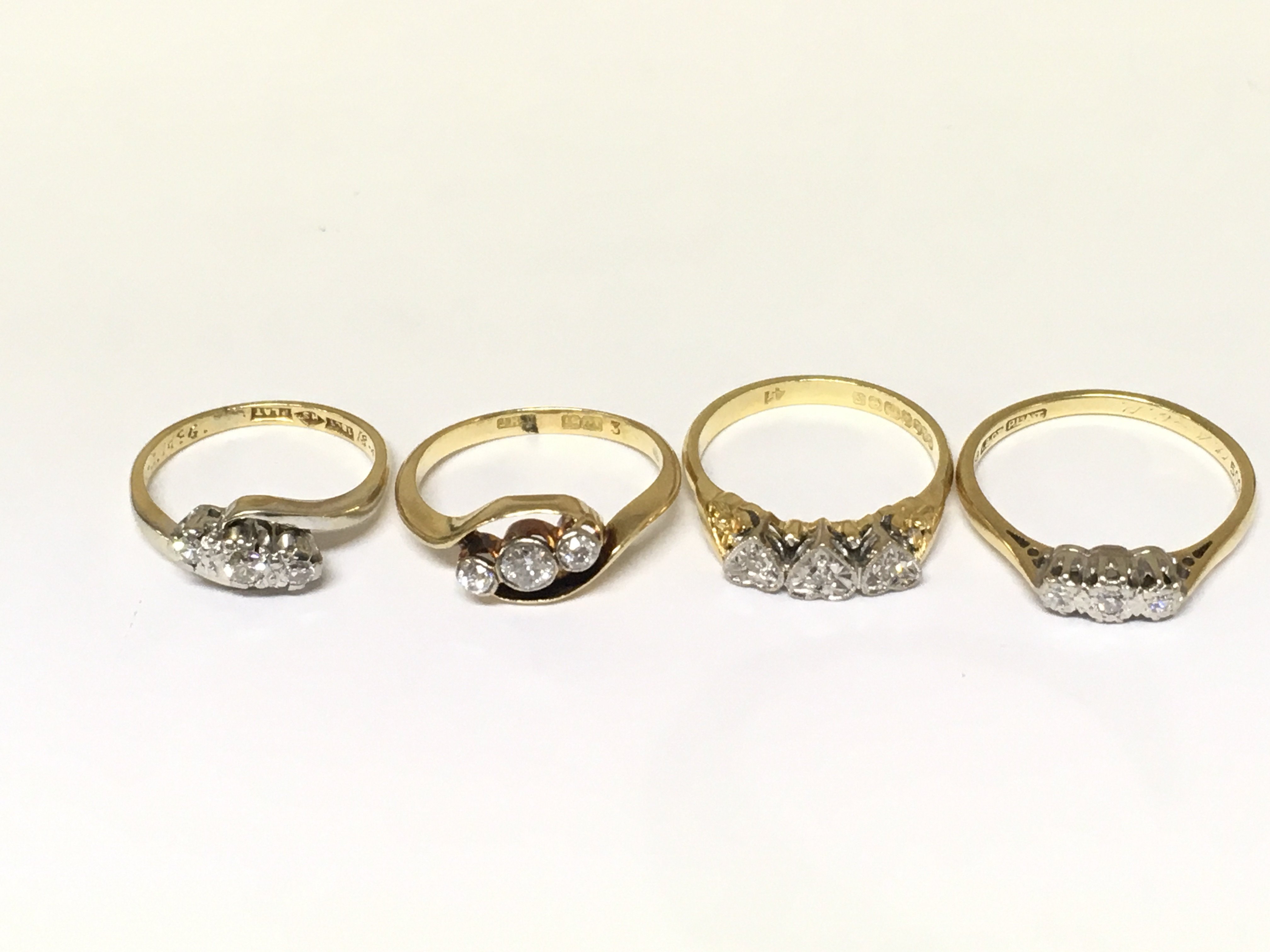Four 18ct gold 3 stone diamond rings. Approximately 10.5g and sizes H K L and O