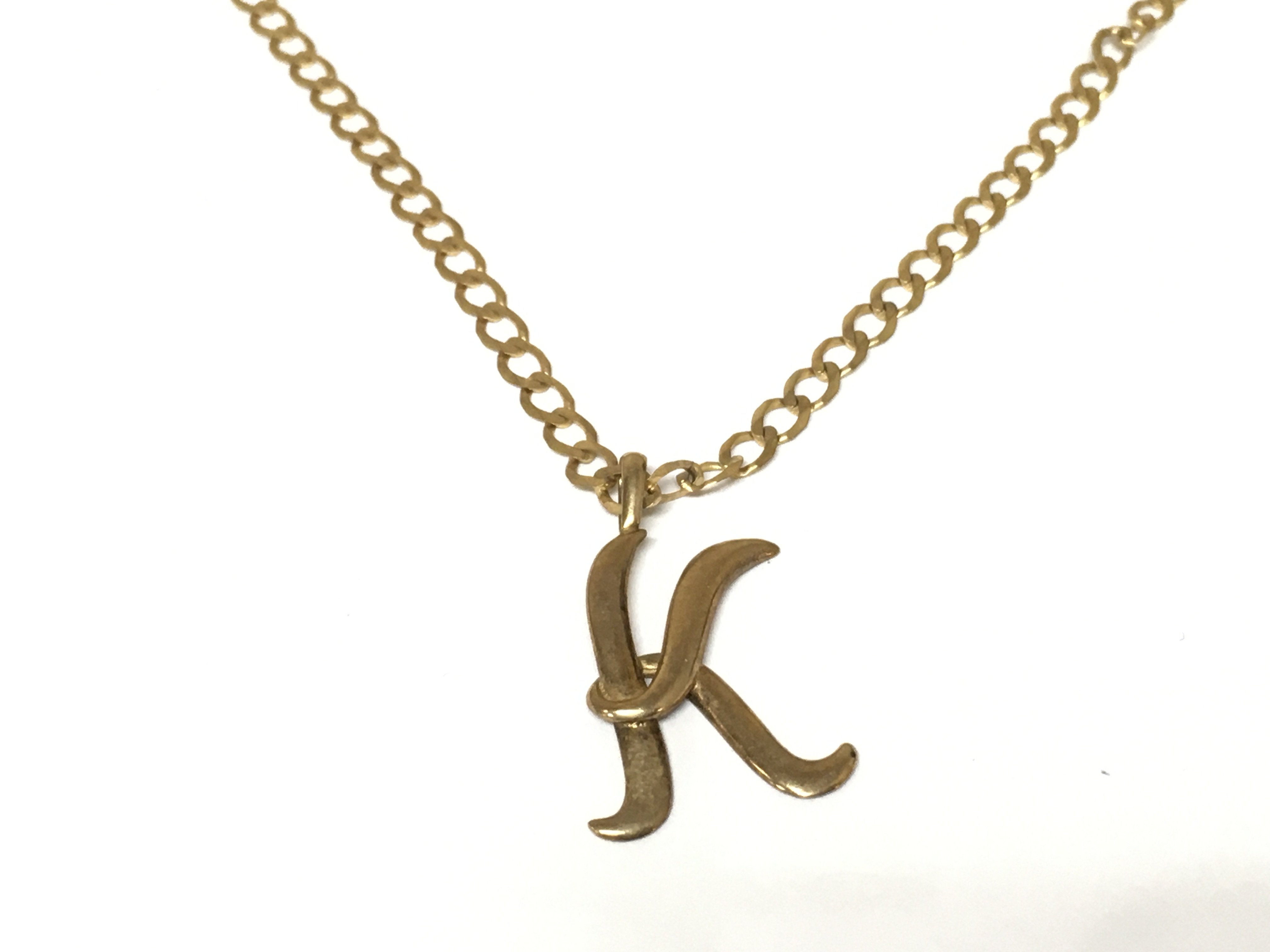 A 9ct gold chain with a yellow metal K pendant attached. 5.13g Postage A