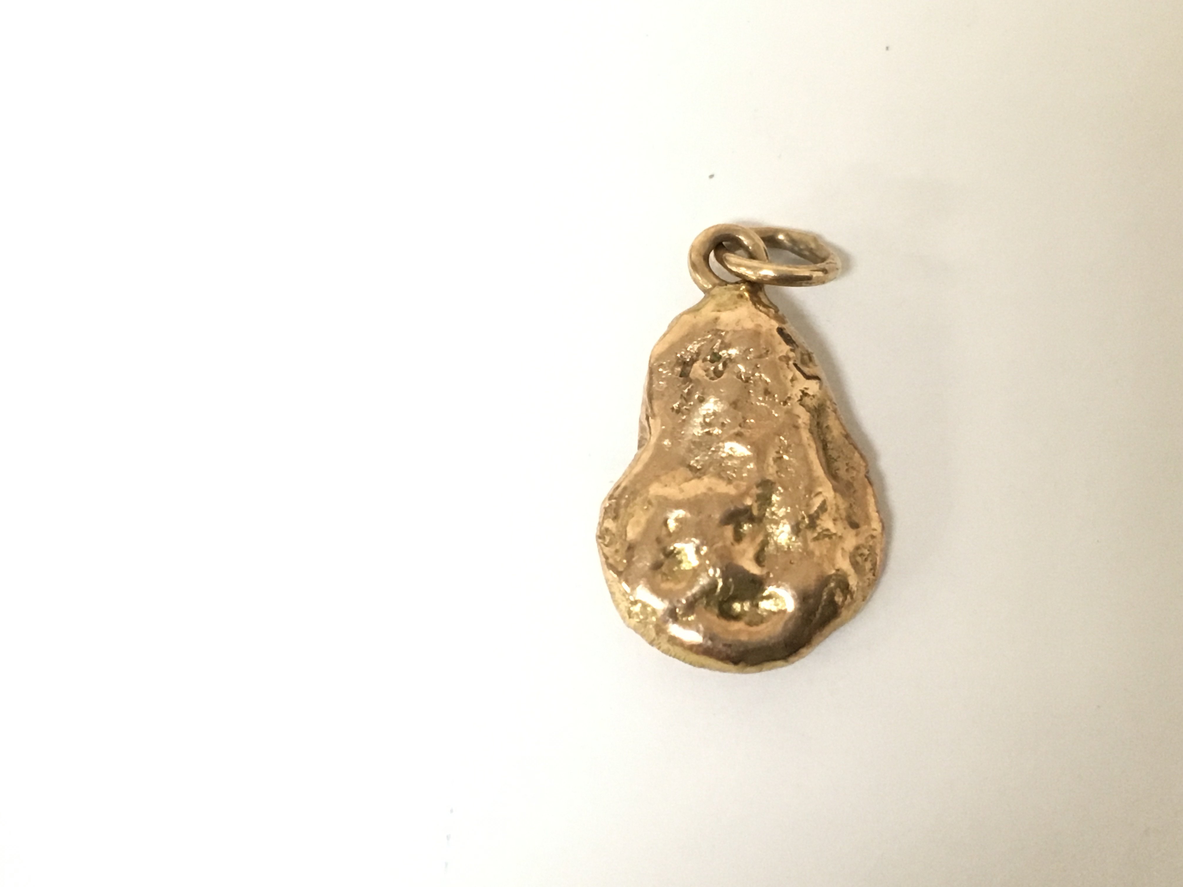 A small unmarked gold pendant in the form of a nugget. 4.92g