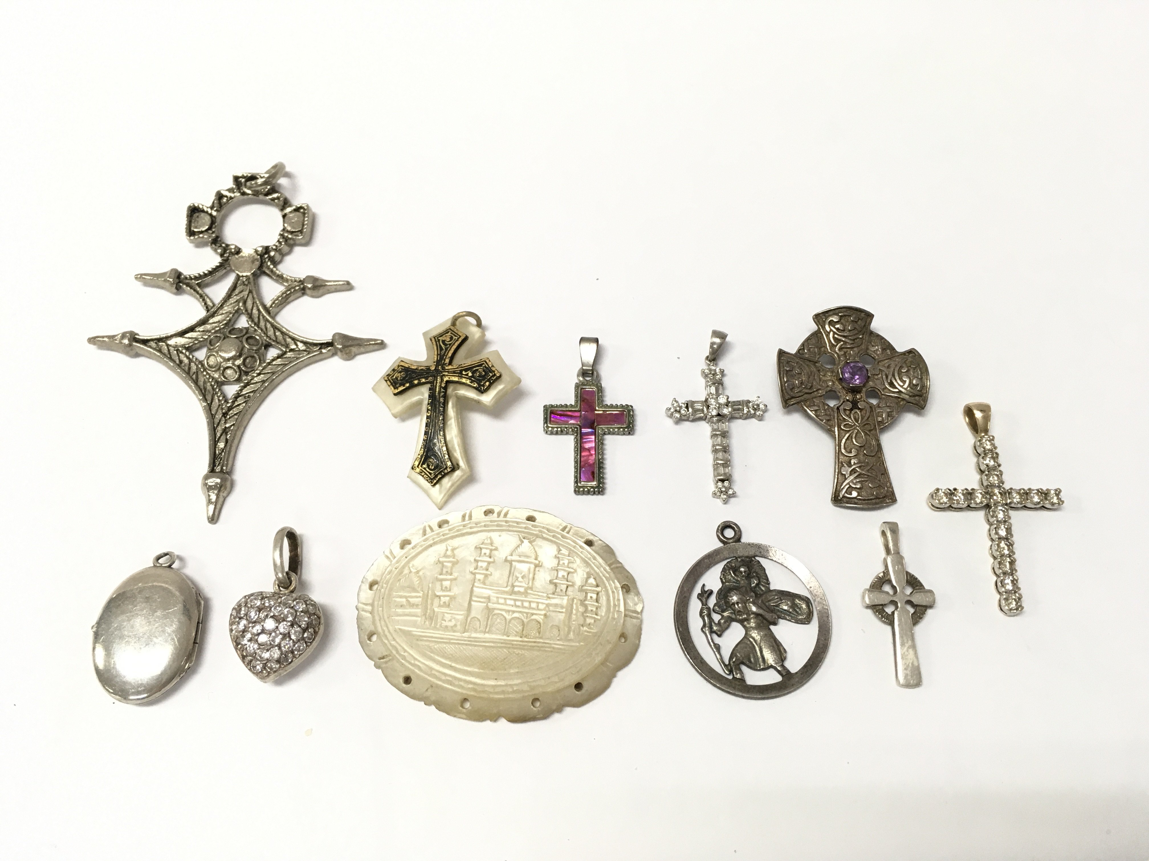 a collection of pendants including mother of pearl, some silver examples and a 9 ct gold cross pendant inset with diamond stones (2.7g total weight) .