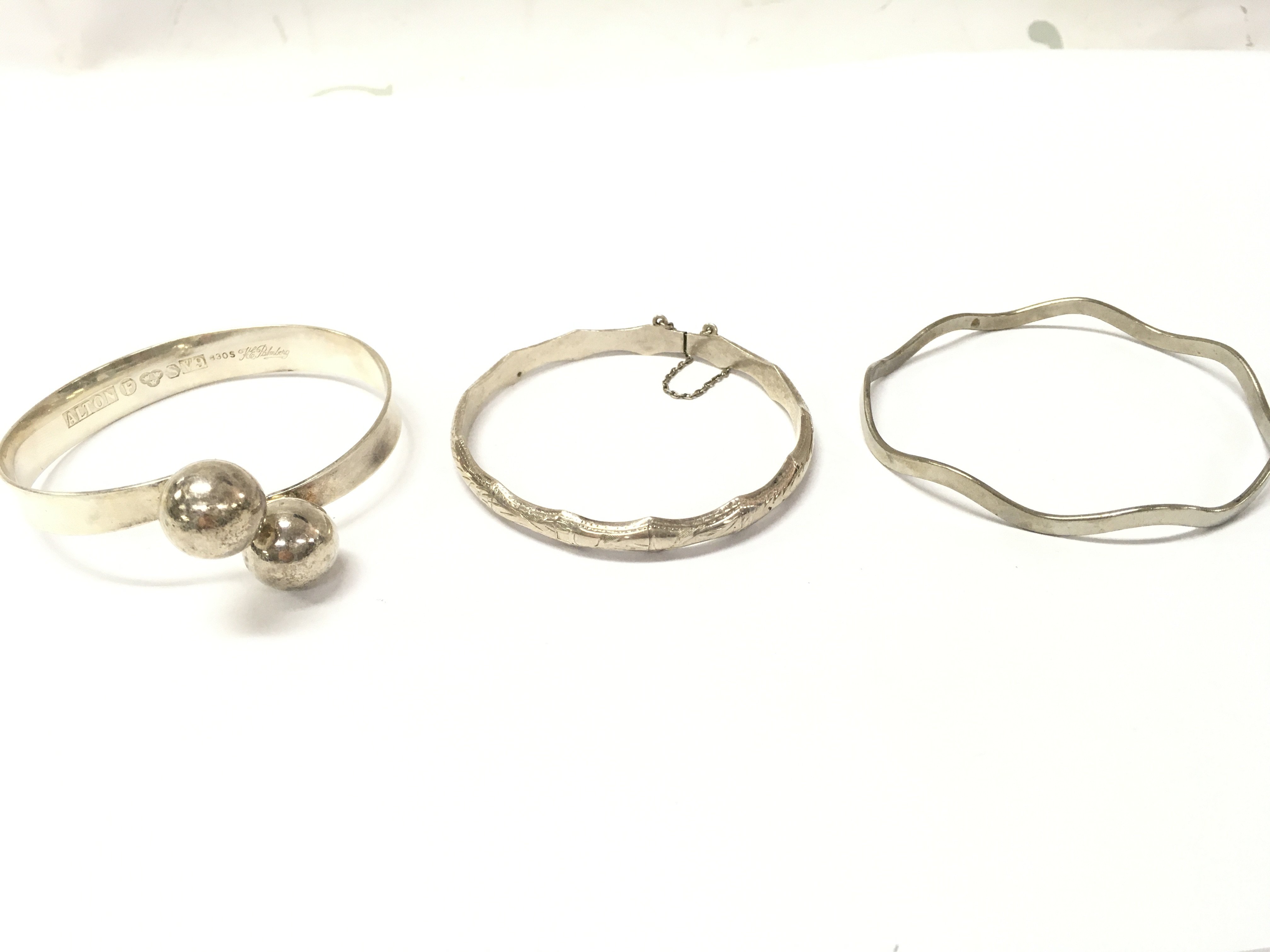 Two silver bangles and one metal. Postage category A