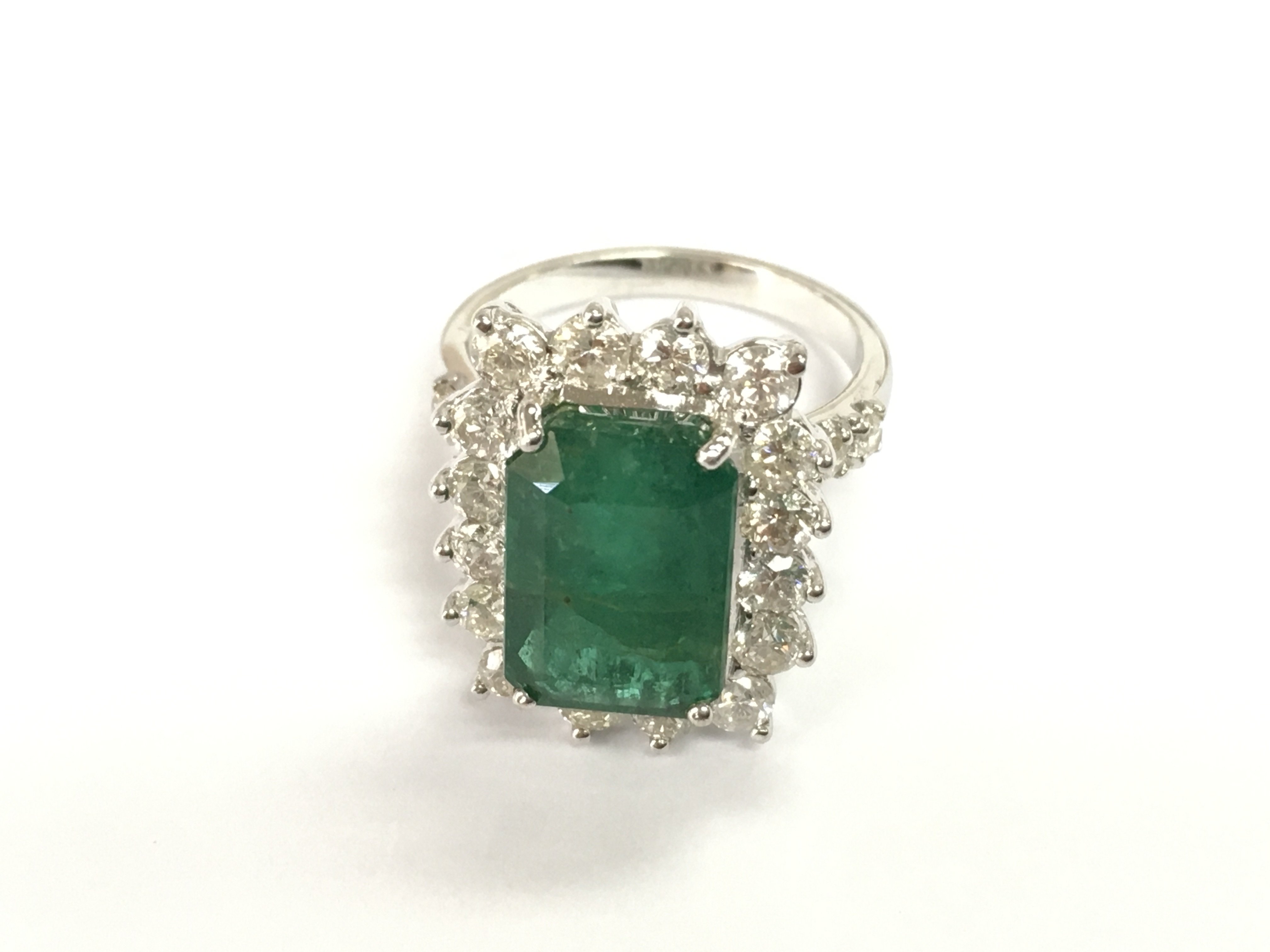 18ct white gold Zambian emerald and diamond cluster ring. Step cut emerald heavily flawed. With gemologists report. Size N