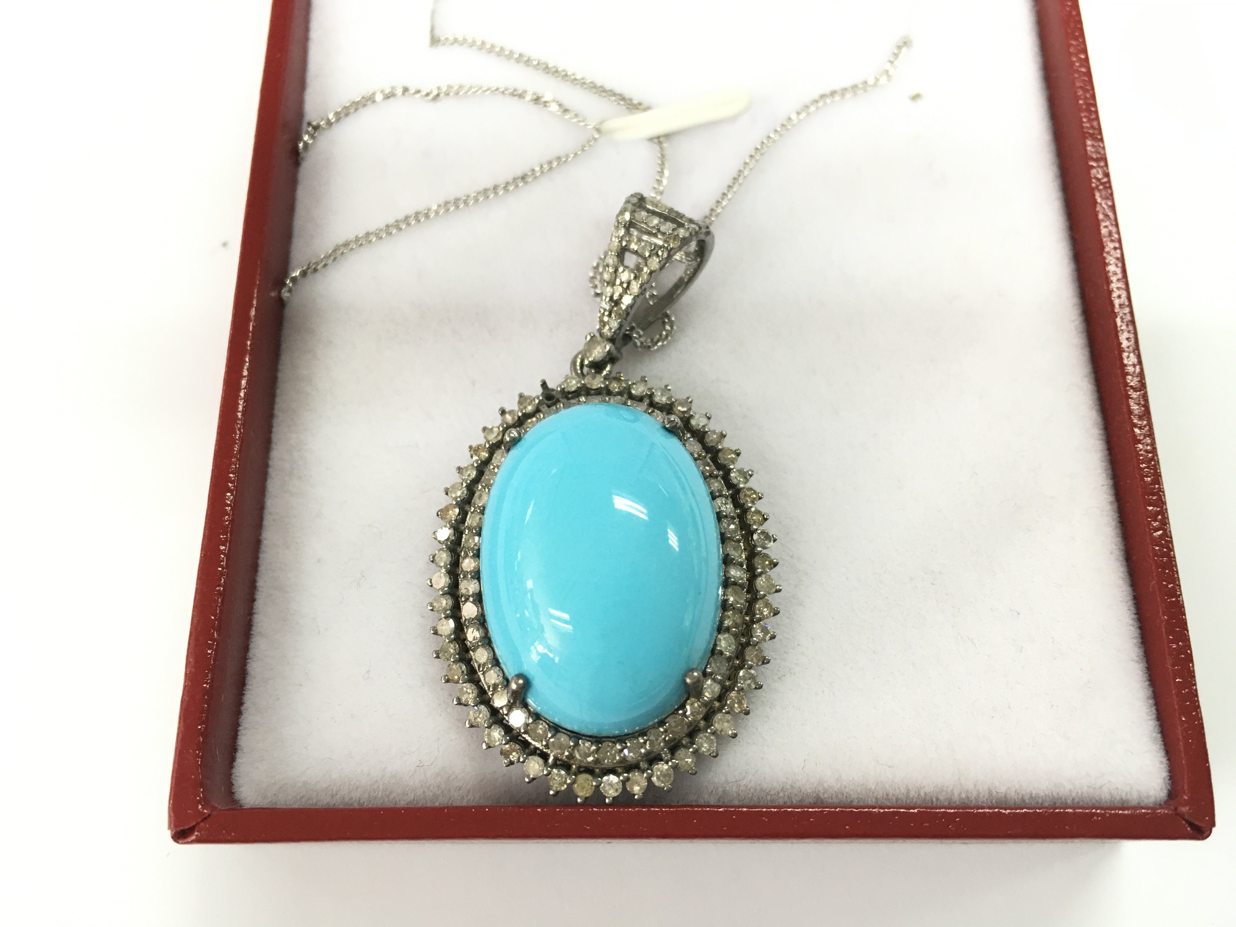Oval pendant in white metal set with a large oval cabochon turquoise and double halo set with diamonds all on a silver chain. Postage B