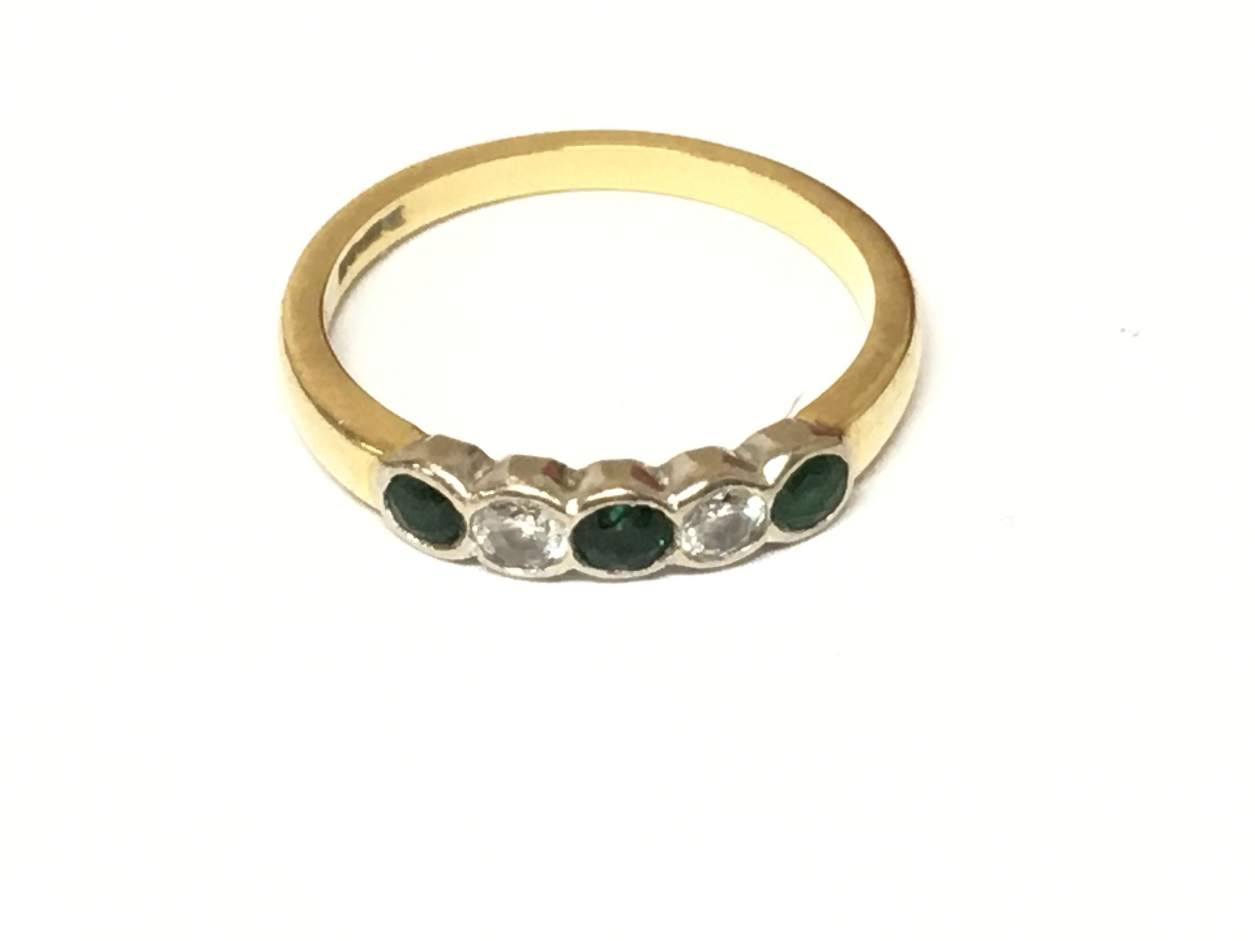 An 18ct gold five stone diamond and emerald ring. Size O and 3.07g