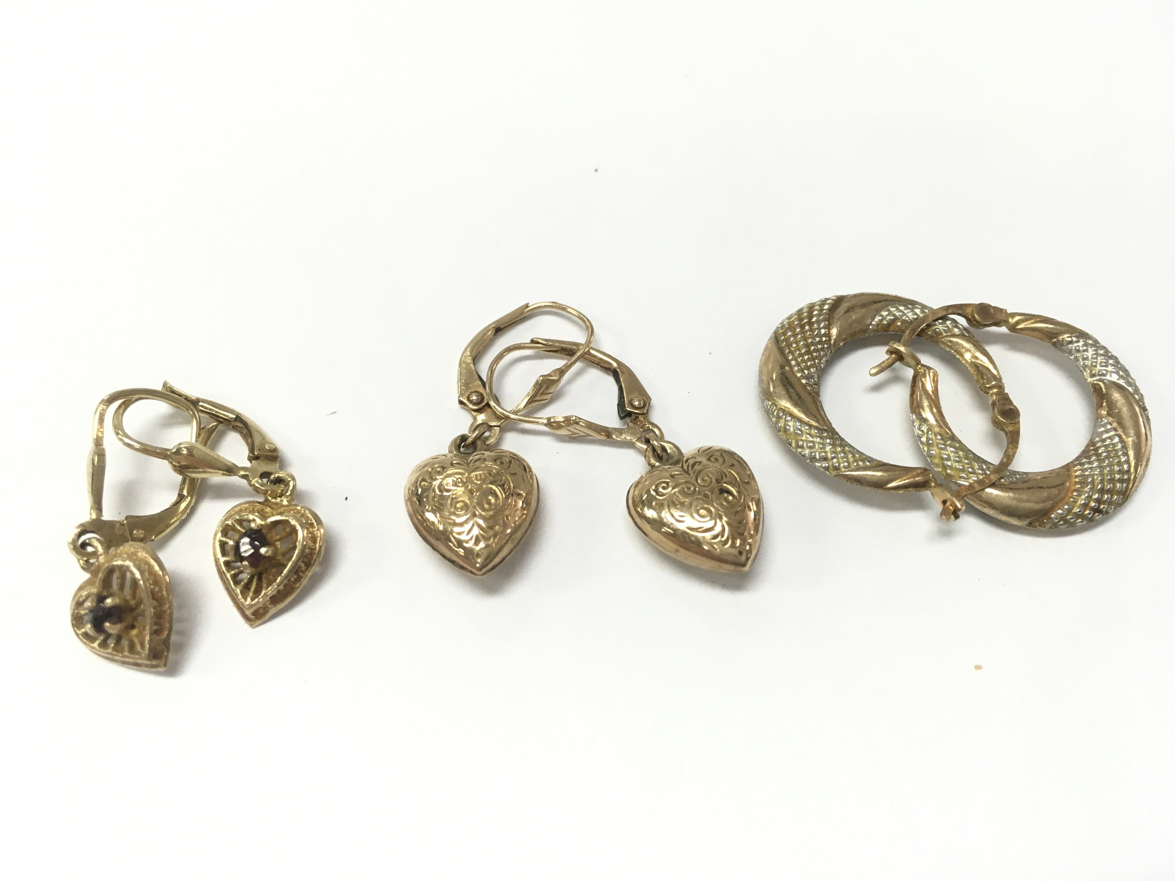 Three pairs of earrings 9ct and 10k. 5g total weight. Also includes some charms some being 9ct and a 9ct gold heart padlock charm . Postage category A