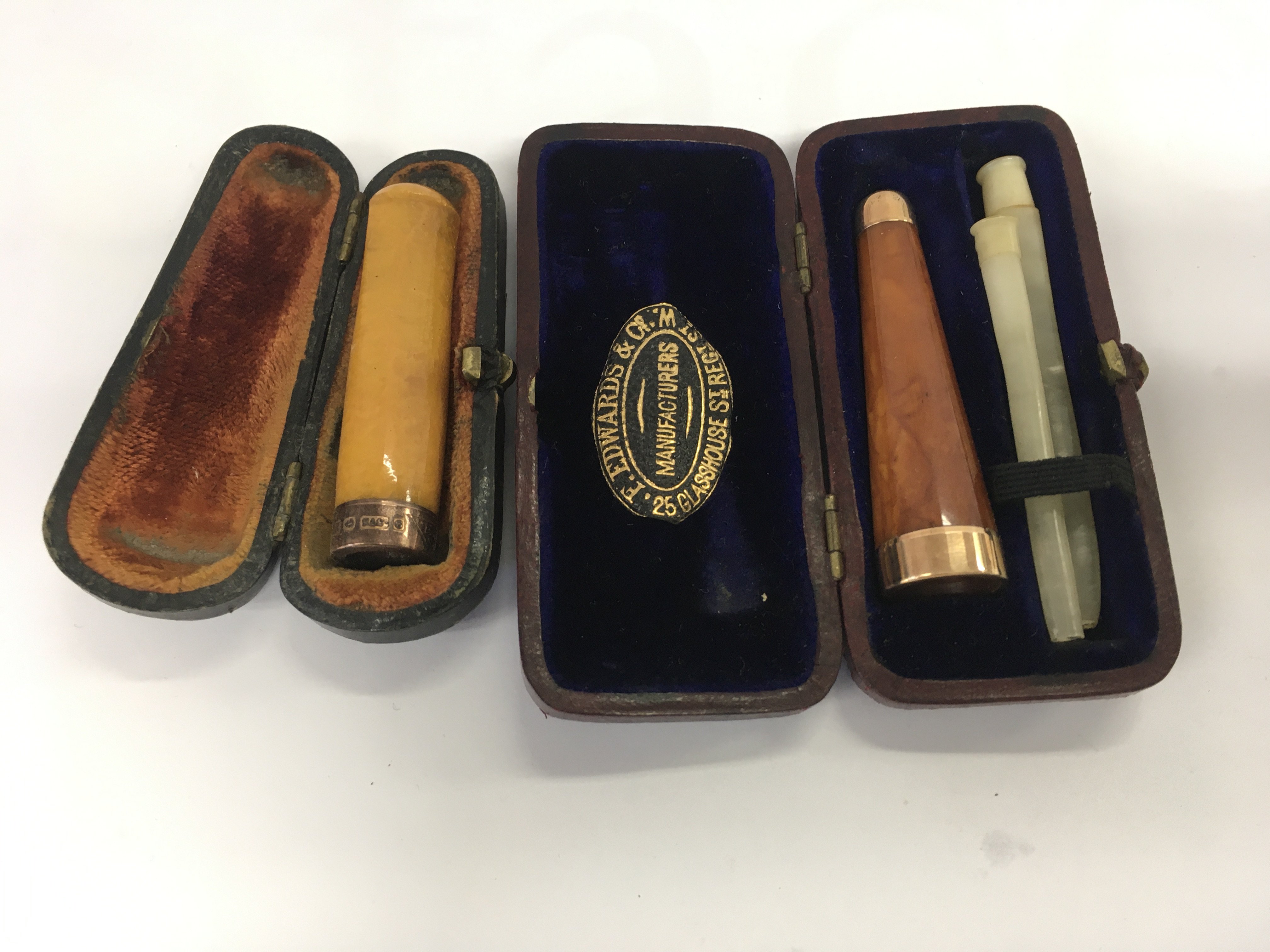 Two amber cigarette holders one marked 9 ct gold .