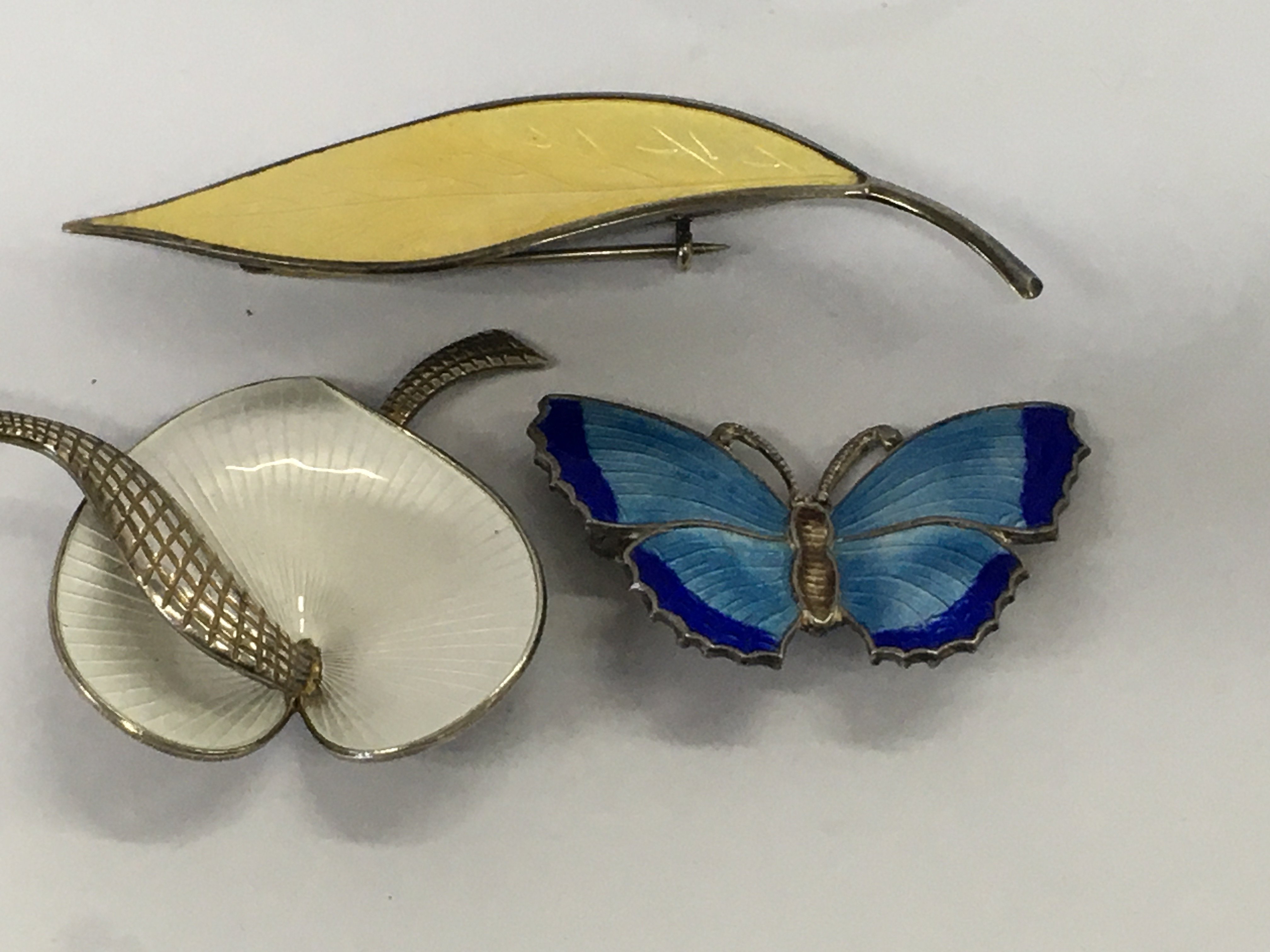 Three silver and enamel brooches butterfly and floral design.