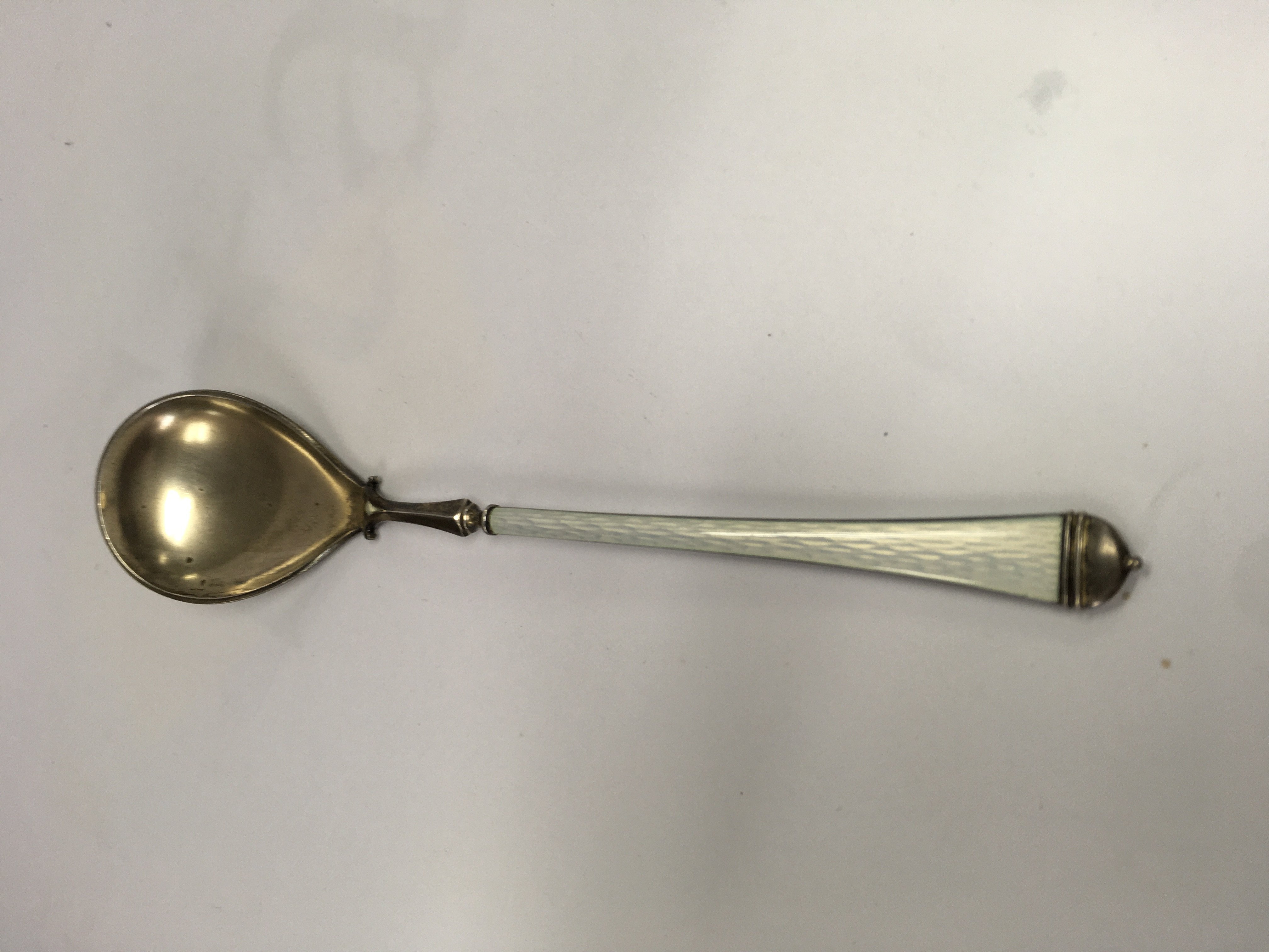 A silver and enamel spoon with tapering handle .