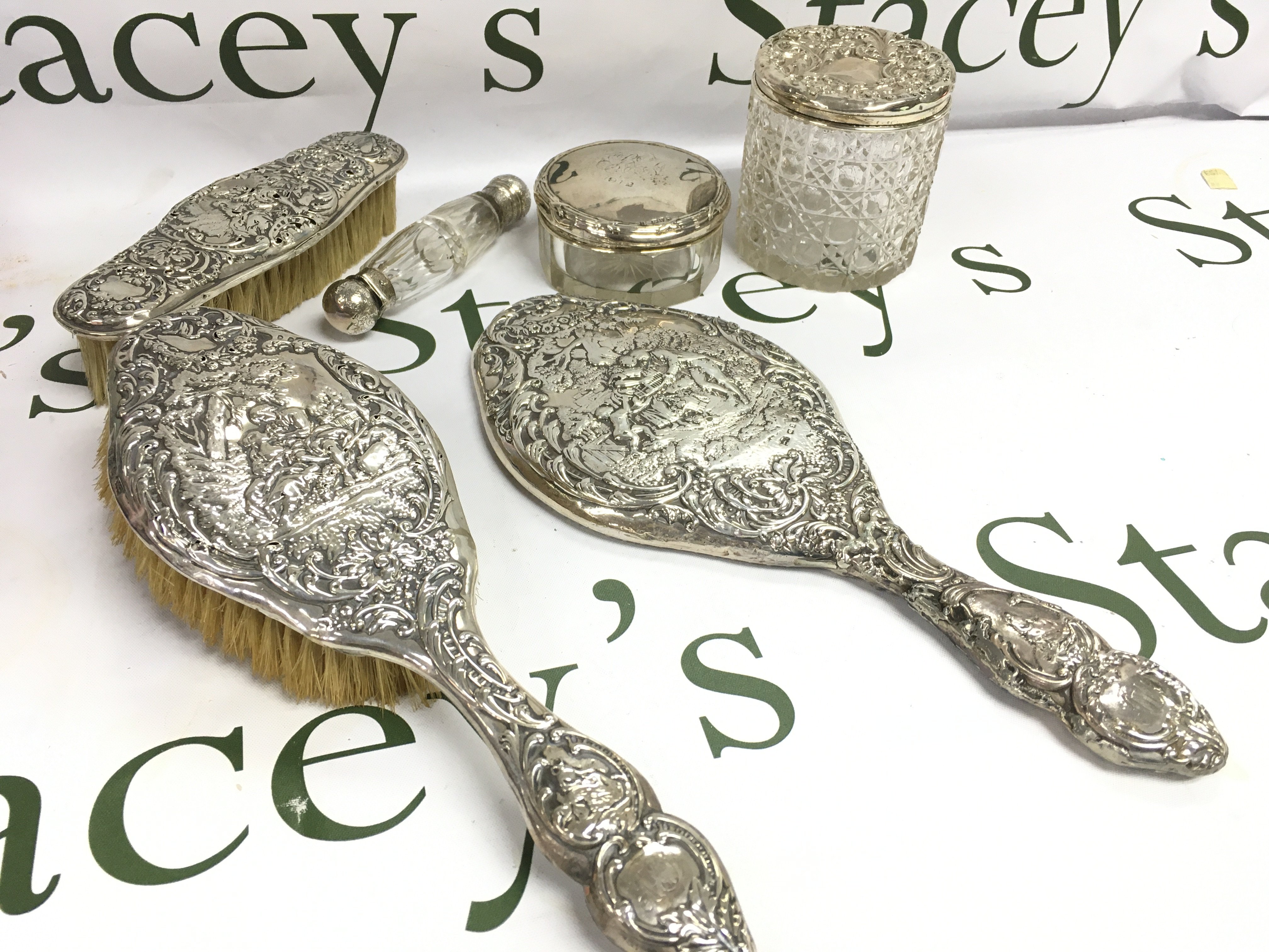 A silver dressing table set includes Brushes, glass jars, double ended scent bottle . This lot cannot be posted