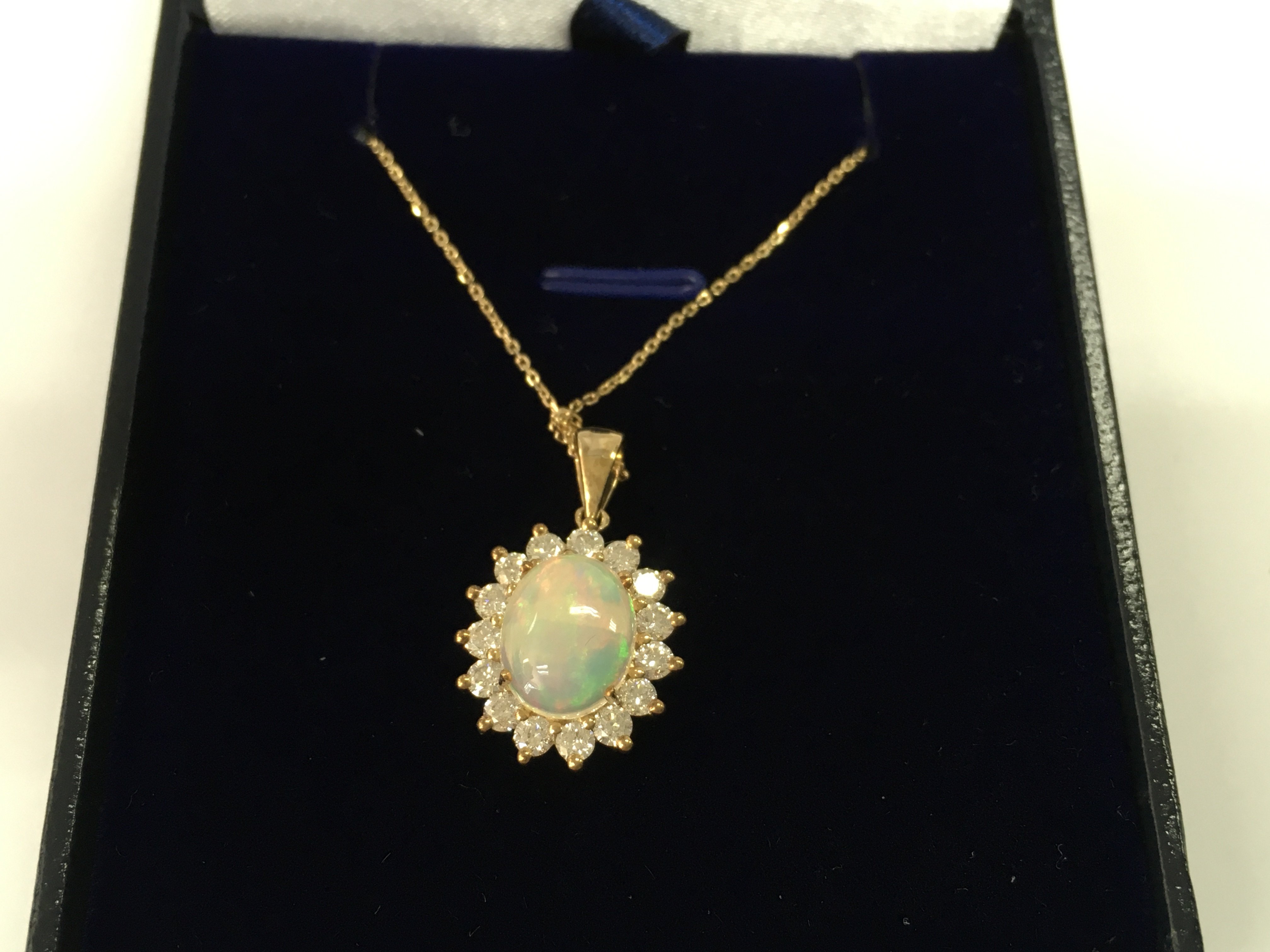 9ct yellow gold oval cabochon opal and diamond cluster pendant on a 9ct gold chain. Opal 1.64ct and diamond 0.74ct