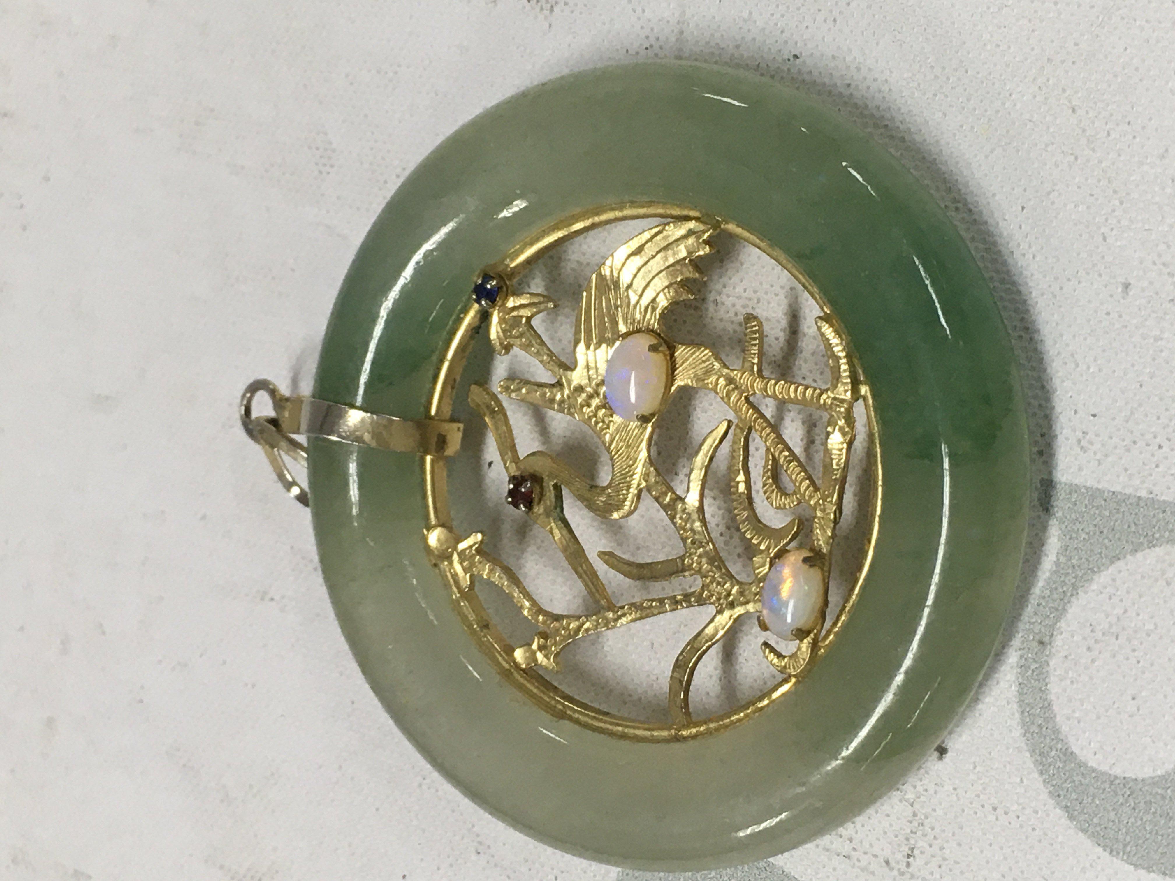 A jade pendant the centre with a design of a stork with gem stone inset .