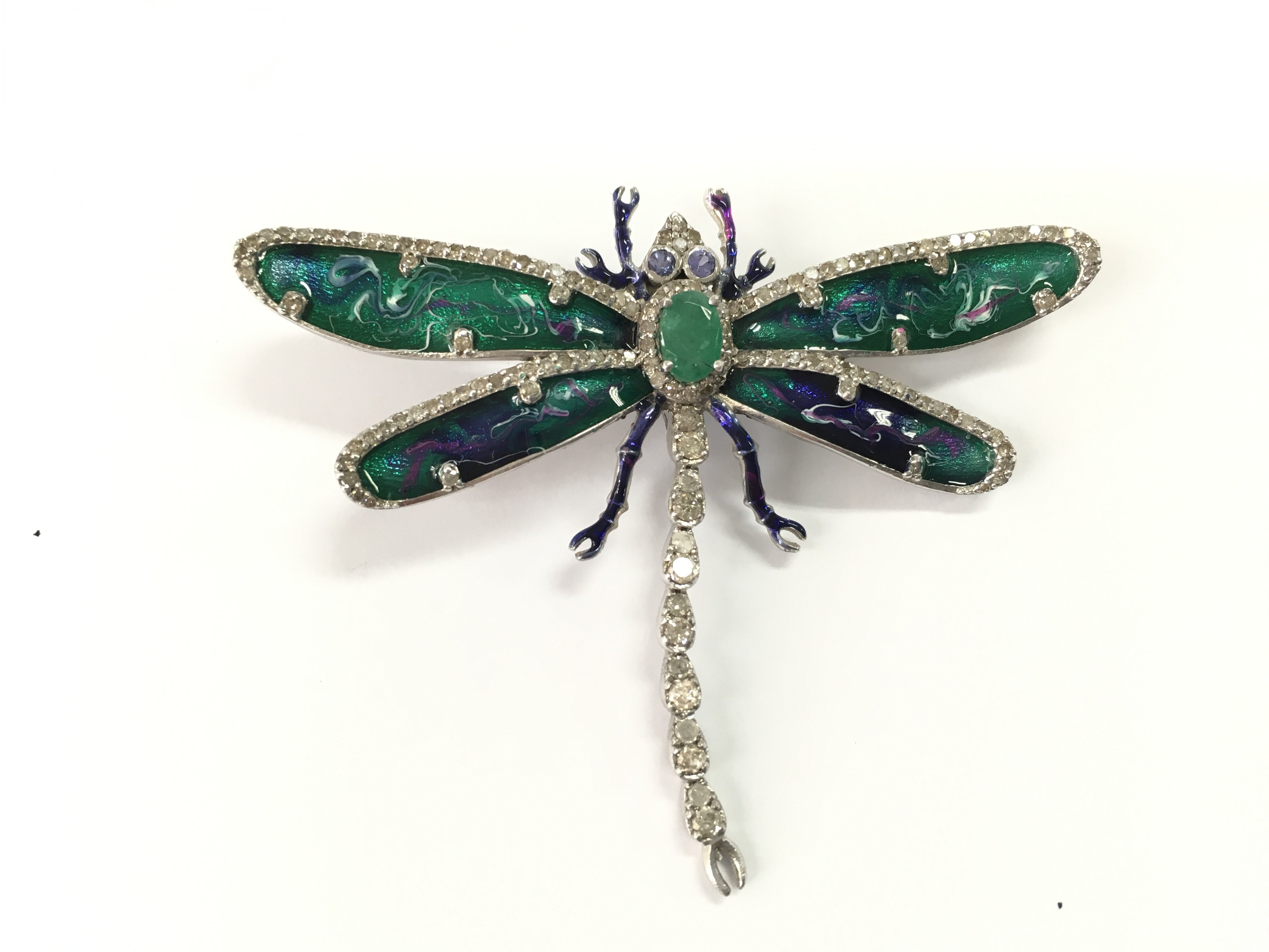 Silver dragonfly brooch set with emerald tanzanite eyes and diamonds with enamel wings. Emerald 0.57ct diamonds 1.41ct and tanzanite 0.18ct