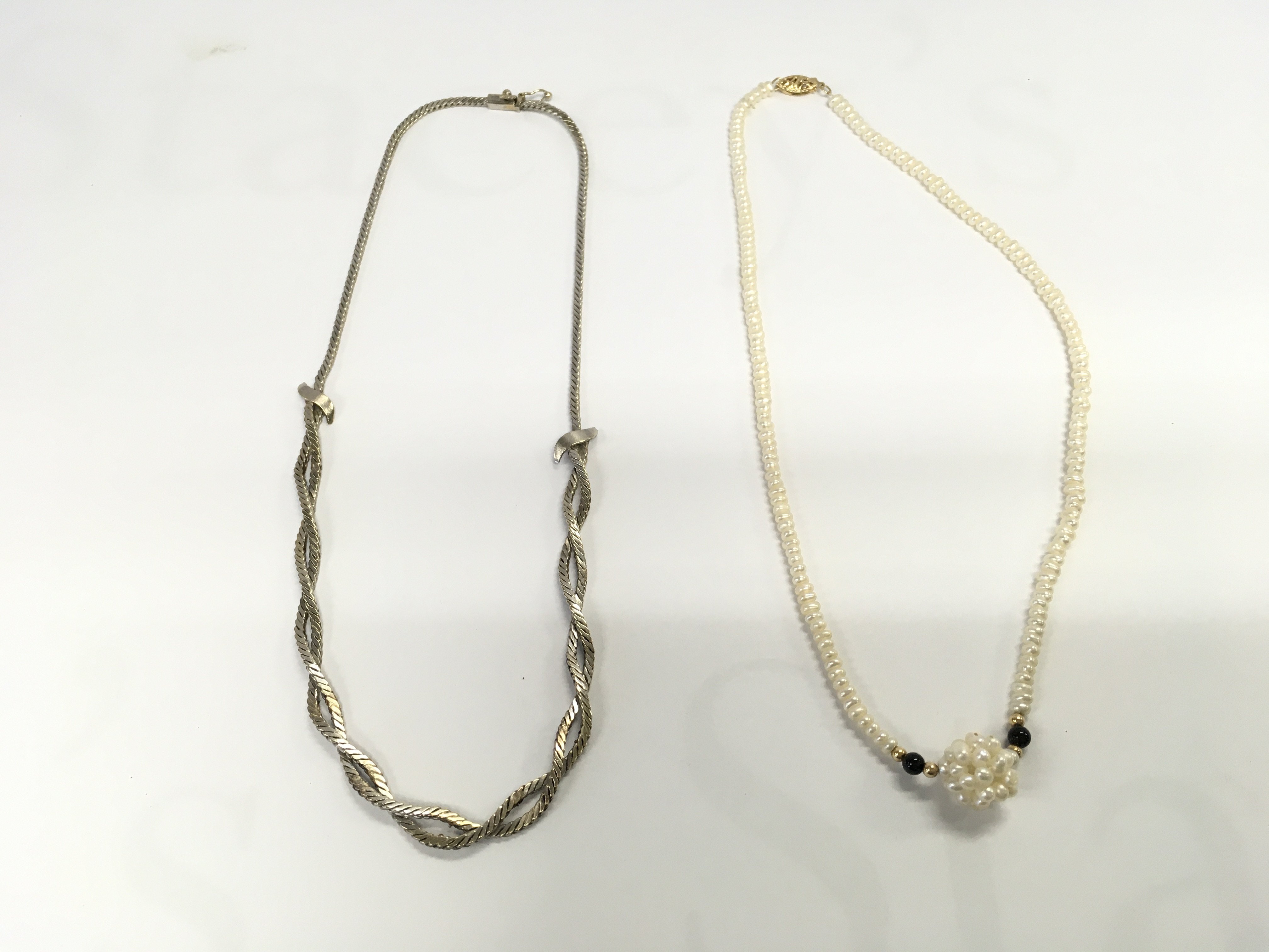 Two necklaces including a pearl necklace and a white metal one. Postage A