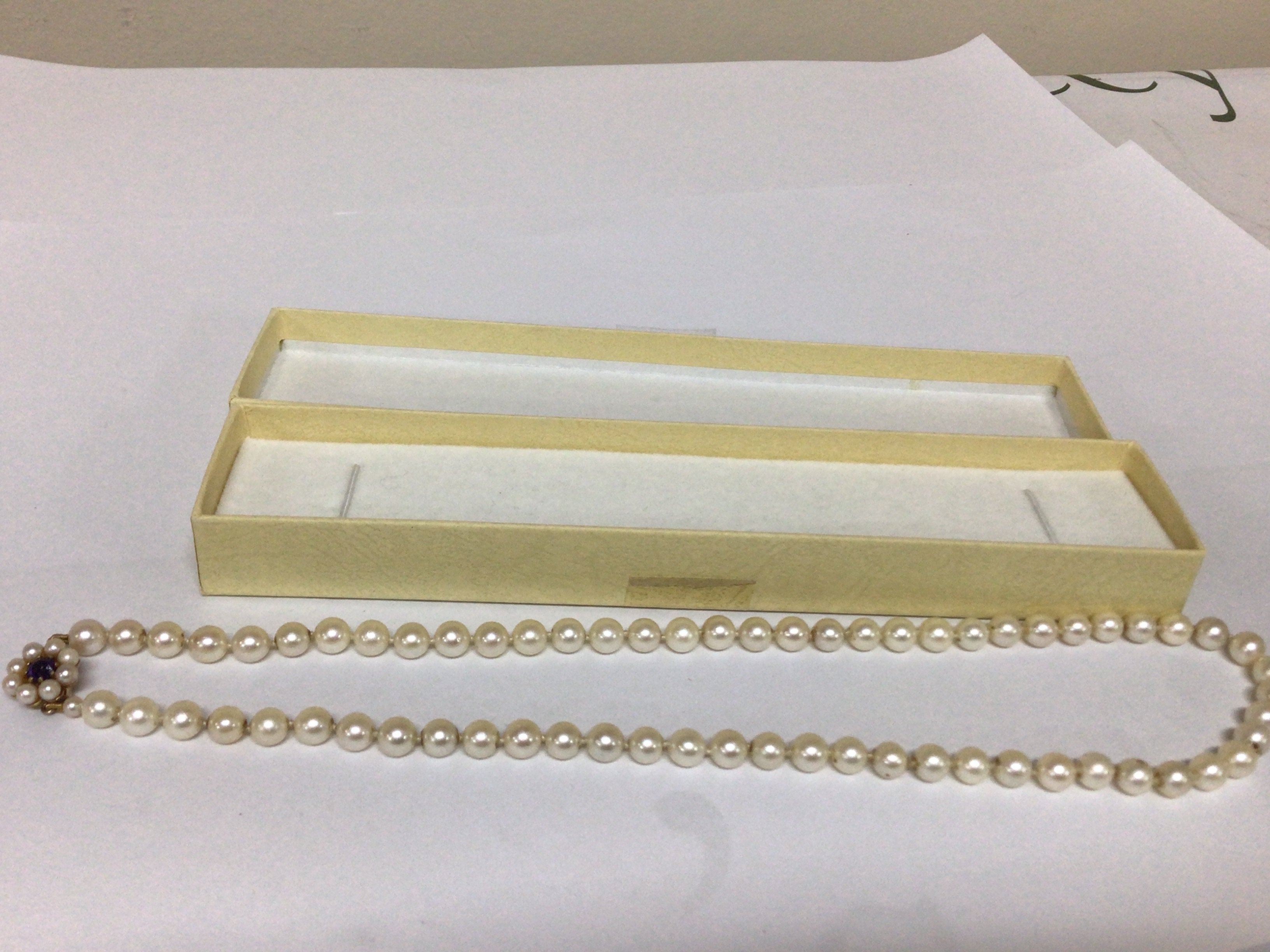 A Pearl necklace with an unmarked gold clasp set with an Amethyst length 48cm approximately. These are possible Mikimoto Pearls.