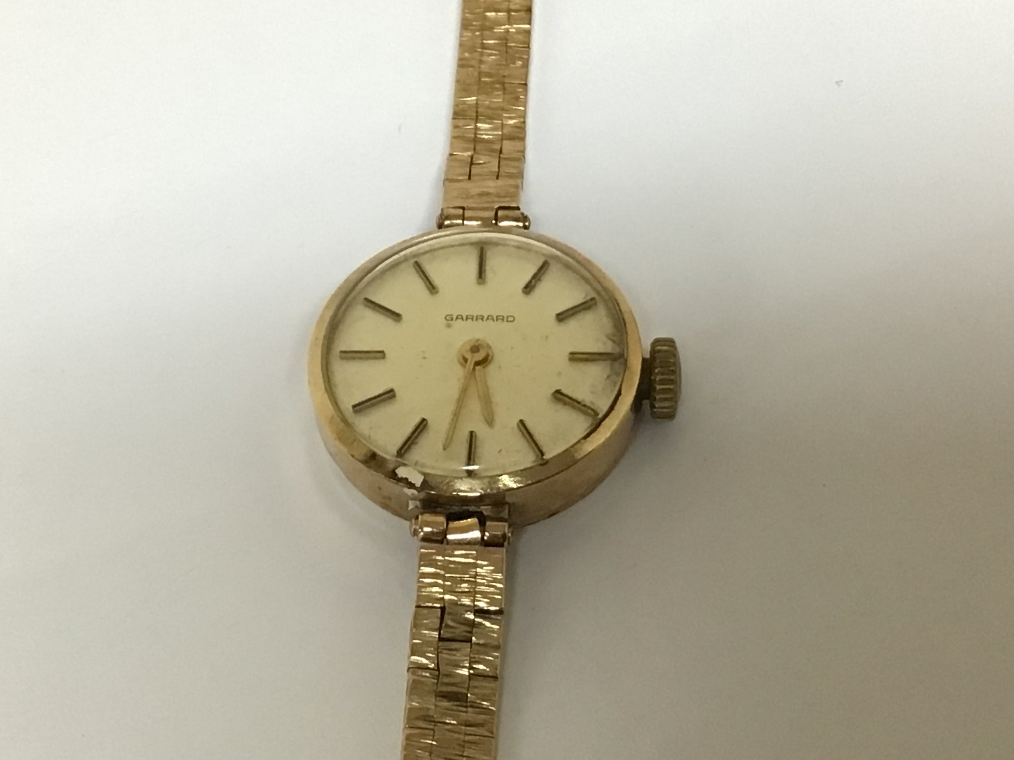 A ladies 9carat gold Garrard Watch with attached 9carat gold bracelet the reverse of the watch with a personal inscription. Weight 17g approximately.
