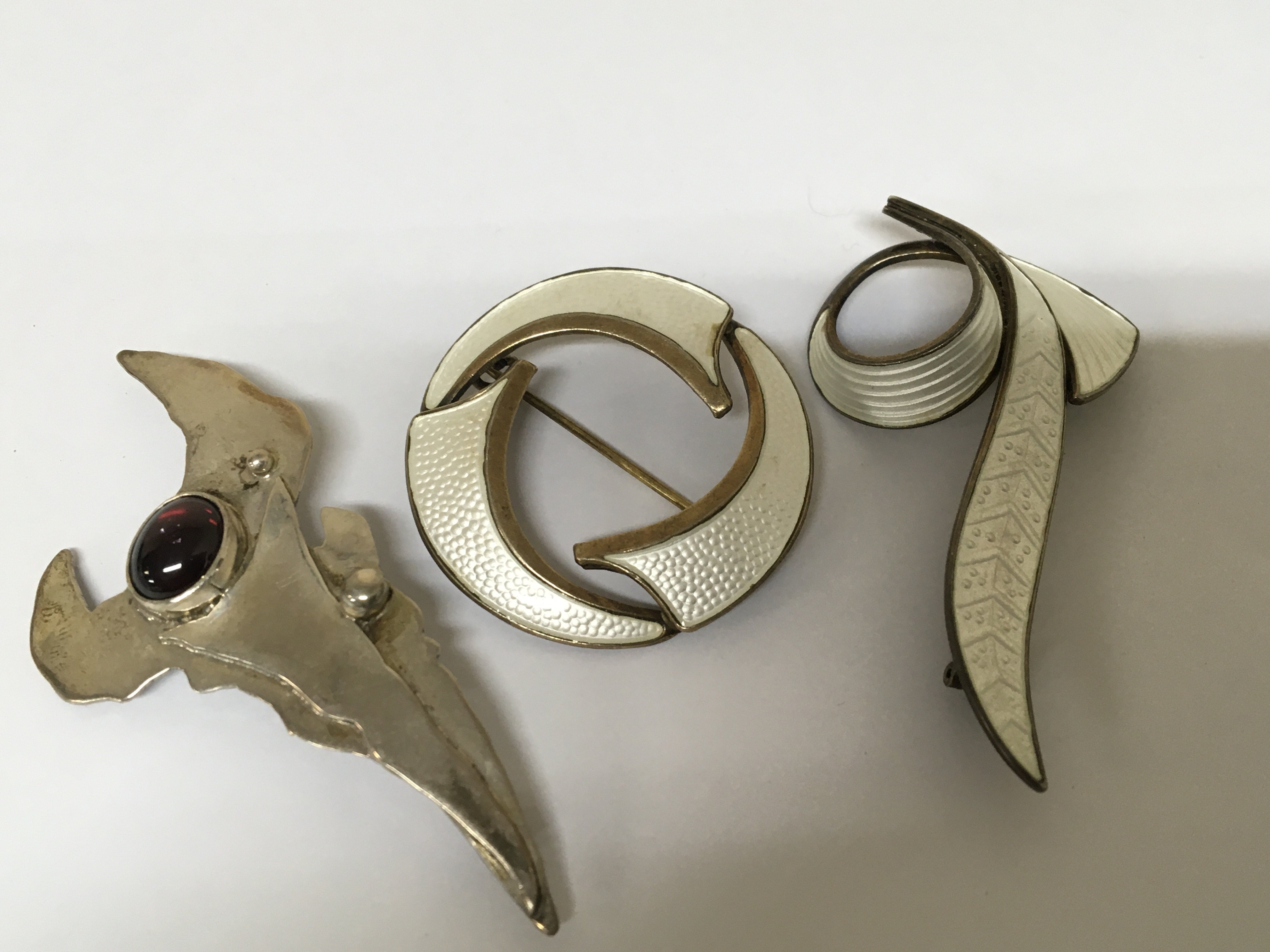 Two silver and enamel modern design brooches and one other silver modern design brooch. (3)